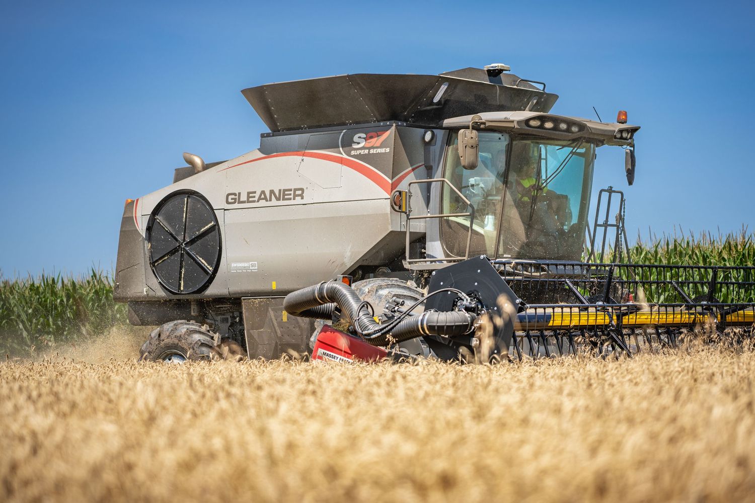Agricultural machinery harvesting wheat in golden fields during sunset. Gleaner S97 in Oshkosh Wisconsin.