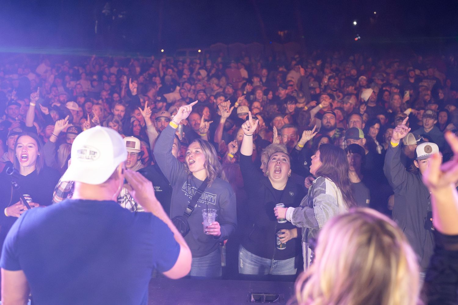 Large crowd of concert attendees dancing and enjoying live music in a dark venue with purple lighting effects. Nashville Pipeline