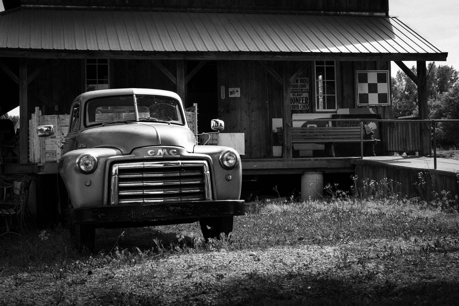 Vintage vehicles and farm buildings silhouetted in black and white composition.