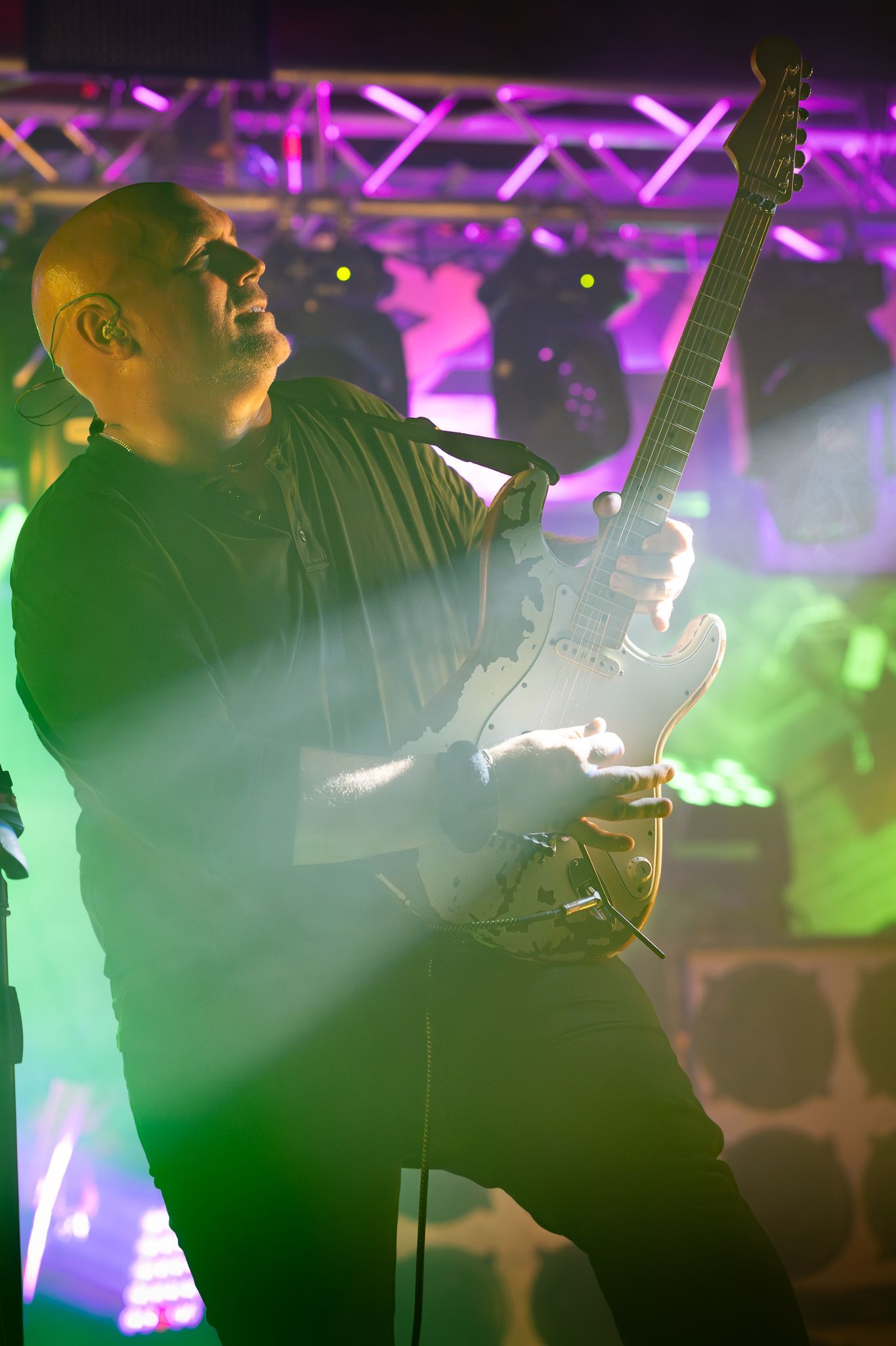 Silhouette of guitarist performing under vibrant purple and green stage lighting. Johnny Wad Band.
