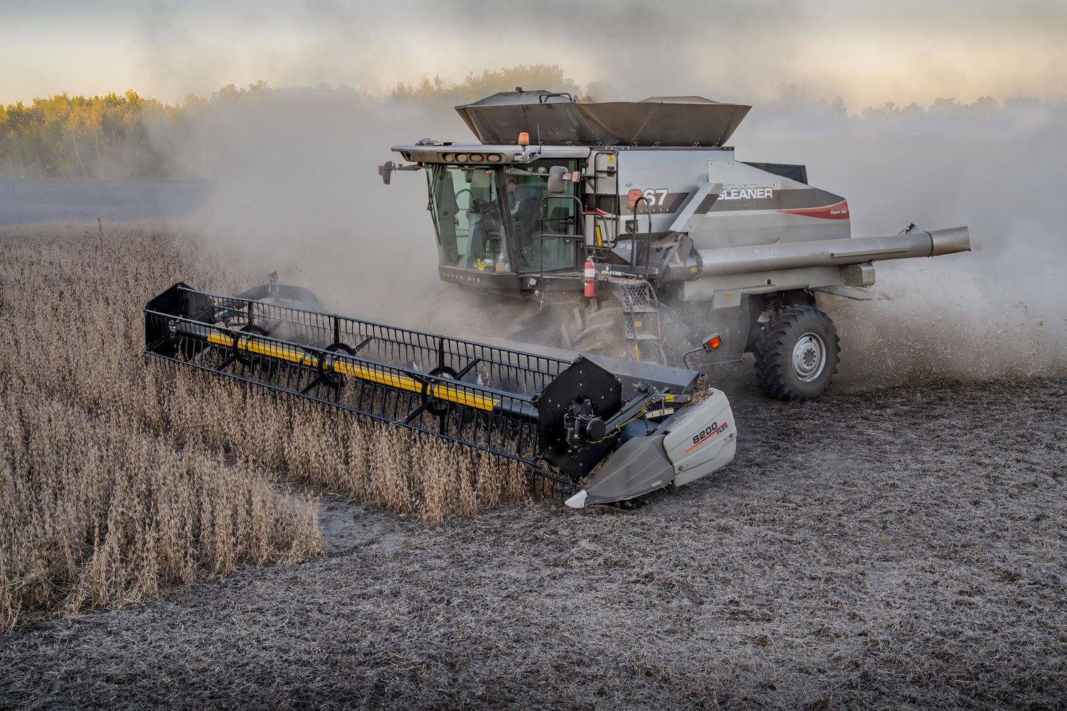 Multiple combine harvesters working in dusty field conditions during harvest season.