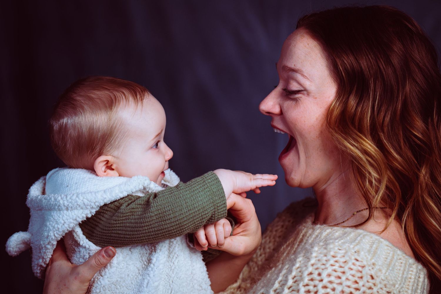A joyful mother laughing and interacting with her happy baby.