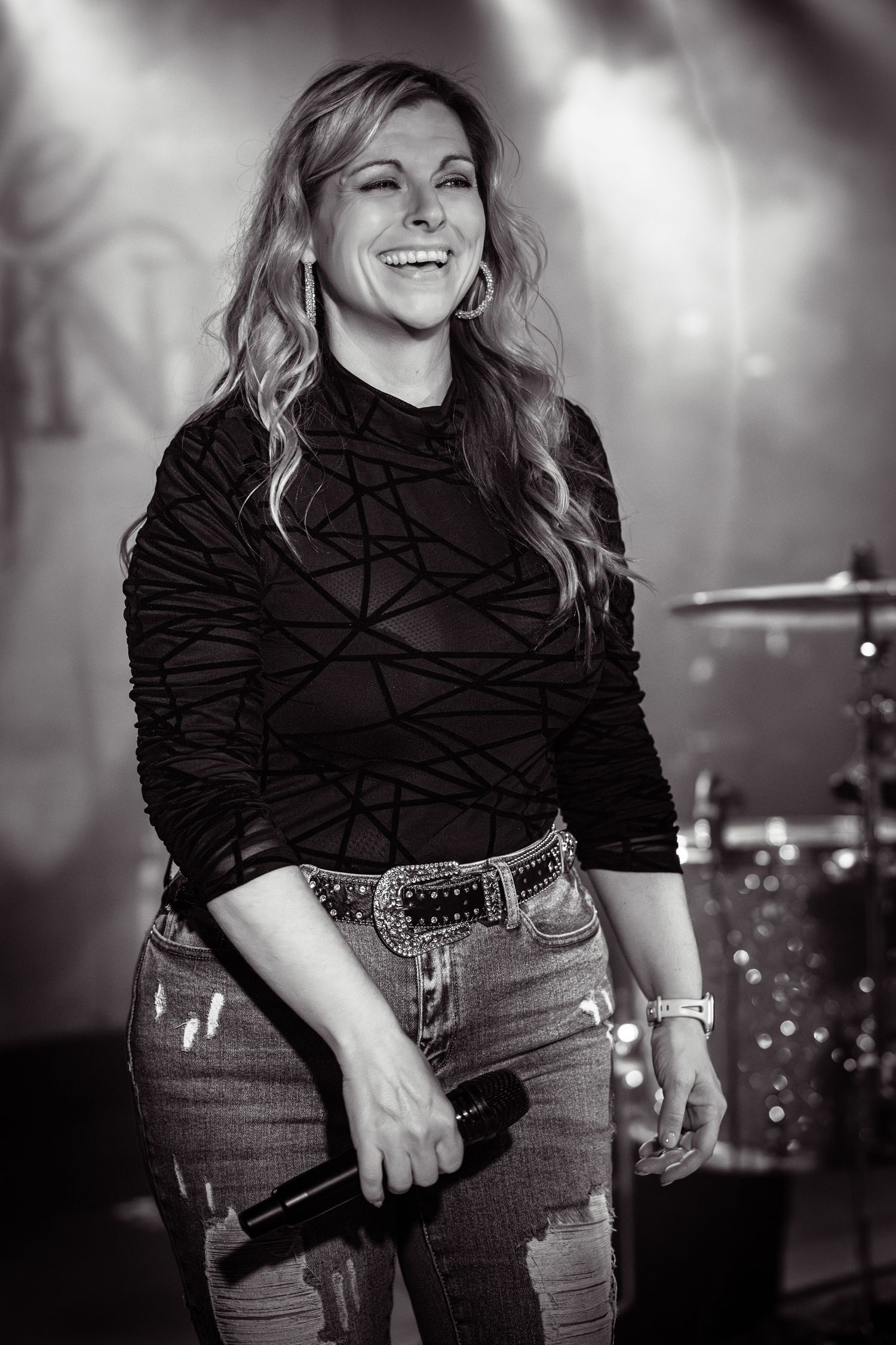 Performer in black top and jeans singing on stage with dramatic lighting. Nashville Pipeline