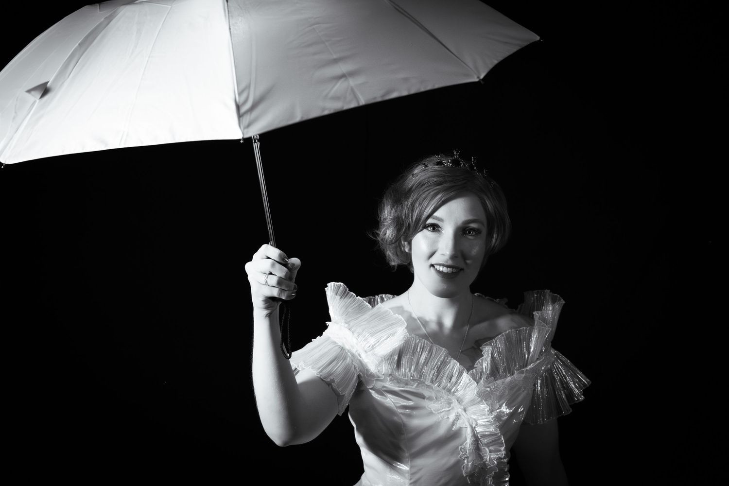Artistic black and white portrait with dramatic lighting and white umbrella prop.