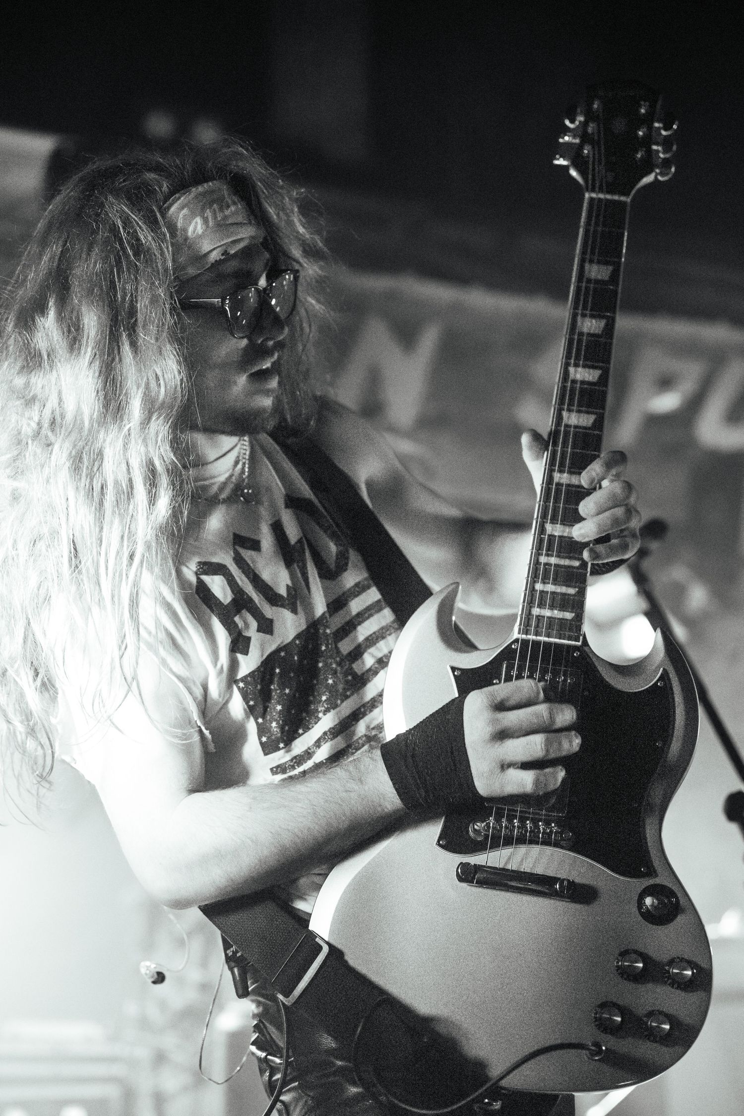 Black and white photo of musician playing electric guitar with dramatic stage lighting.