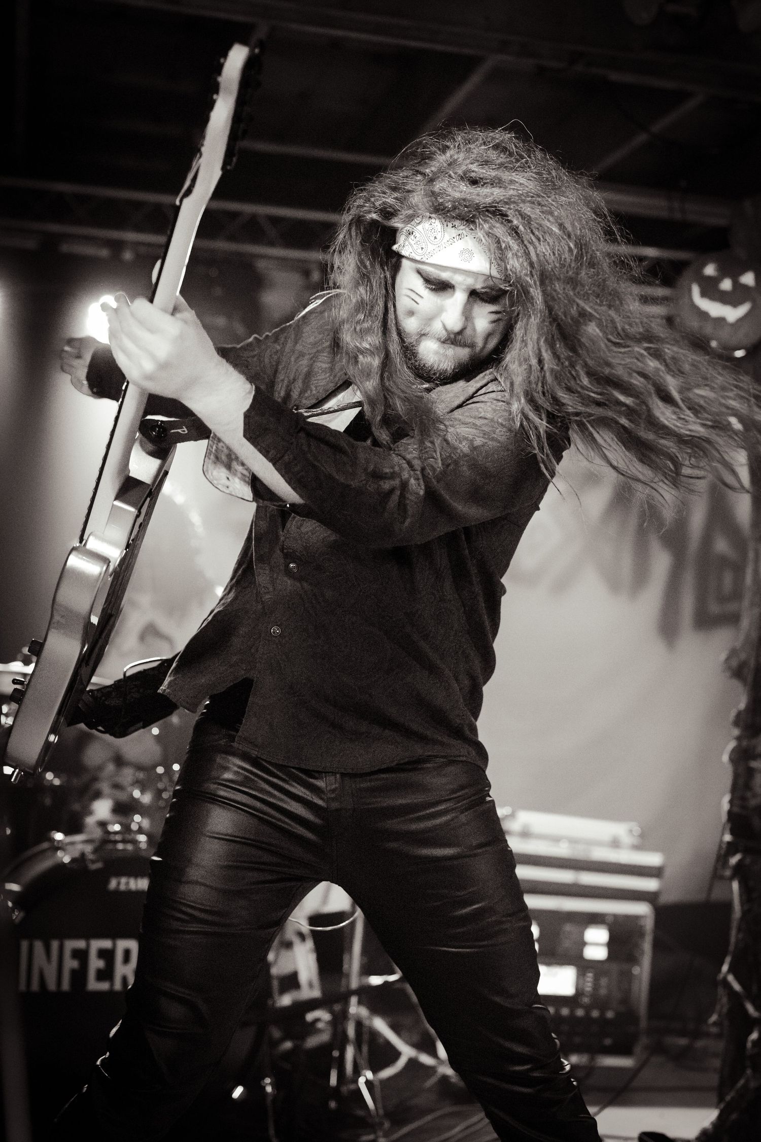 A performer in black clothing moves energetically on a dimly lit stage.