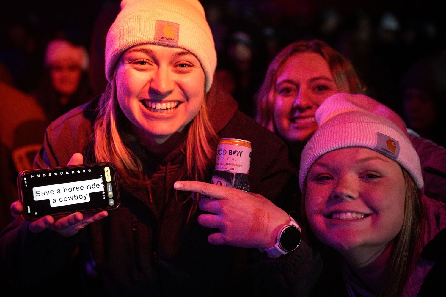 Concert audience enjoying live music performance in dark venue with pink lighting effects.