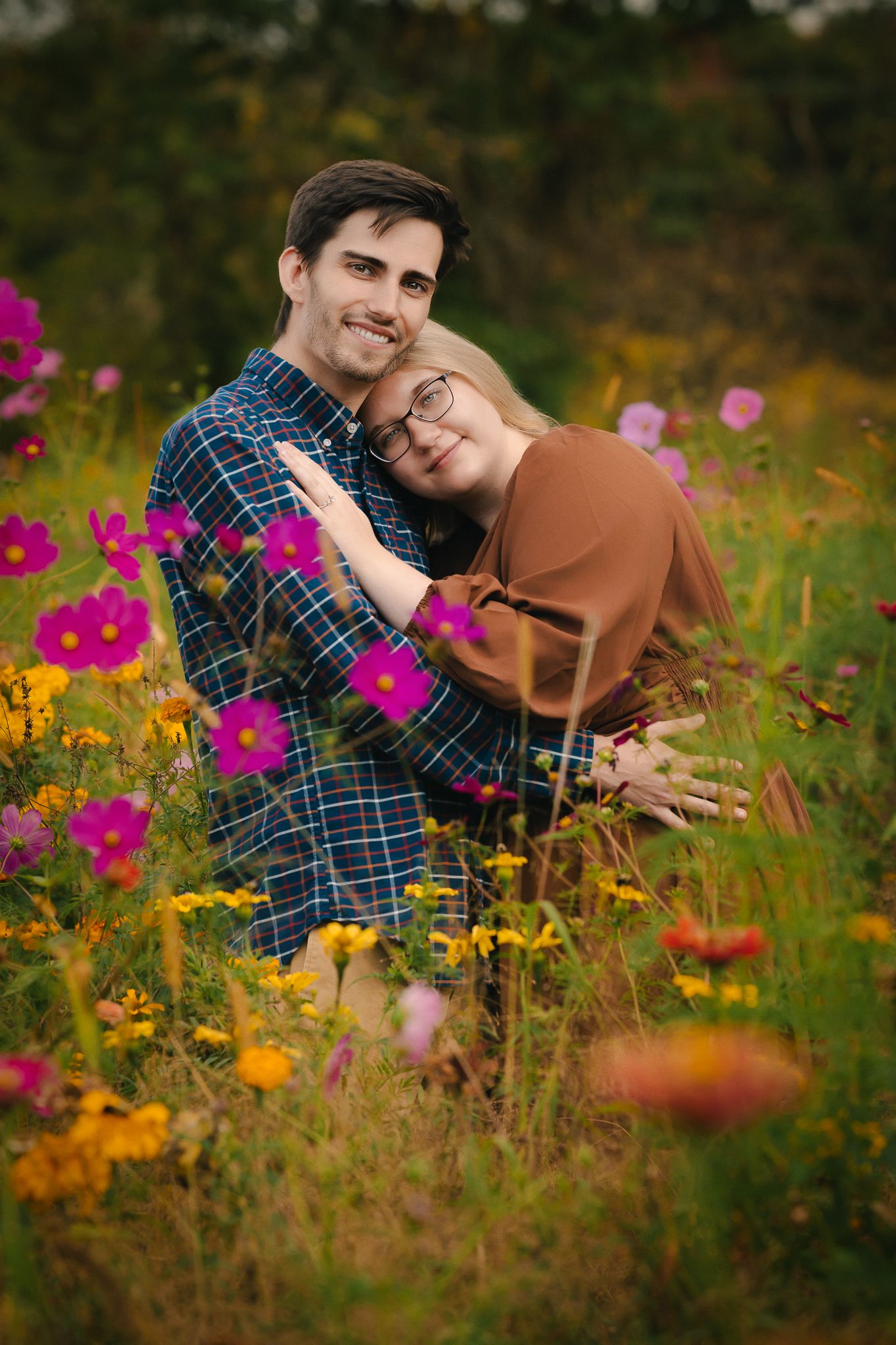 Romantic couple embracing in a vibrant wildflower meadow with pink and orange blooms.