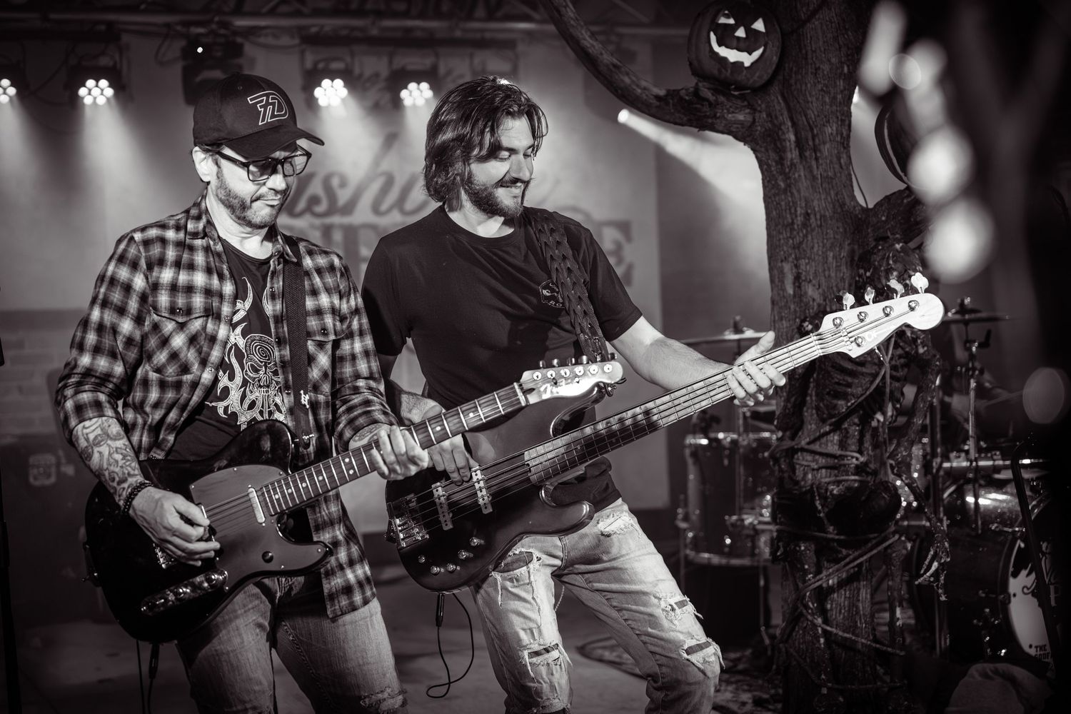 Musicians playing guitars in a dimly lit concert venue wearing plaid shirts. Nashville Pipeline