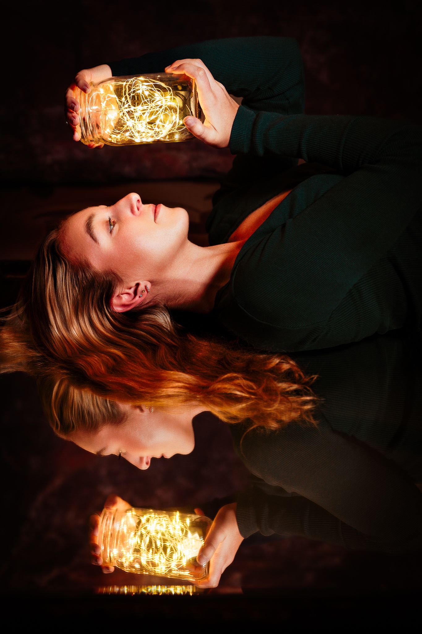 Artistic portrait with glowing fairy lights creating a magical reflection effect in darkness.