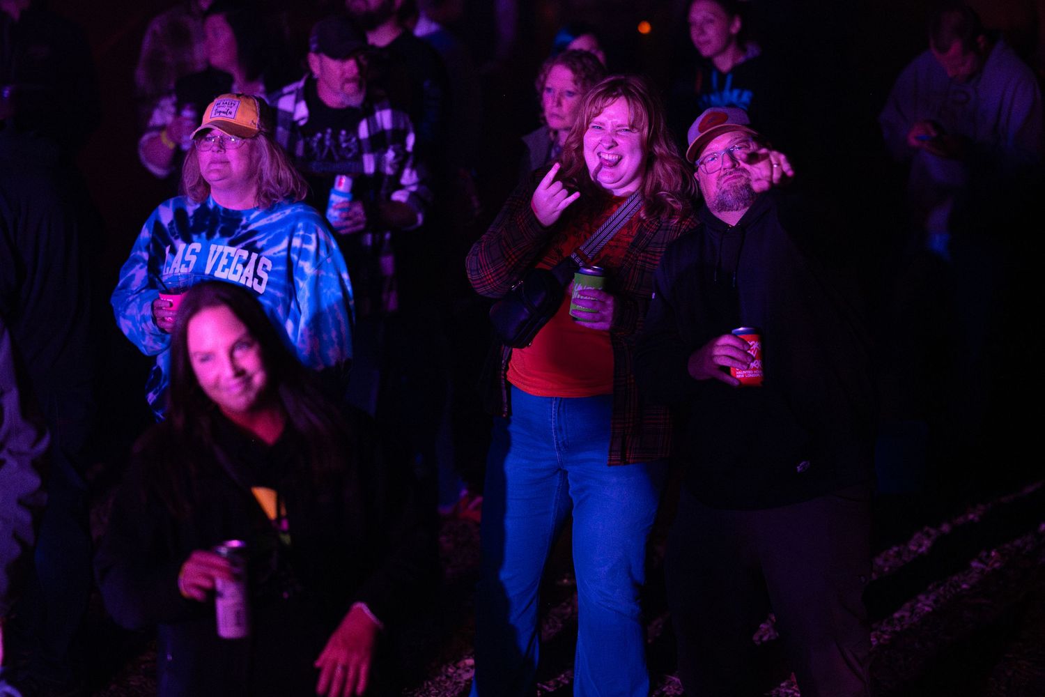Concert audience bathed in purple lighting enjoying a live music performance.