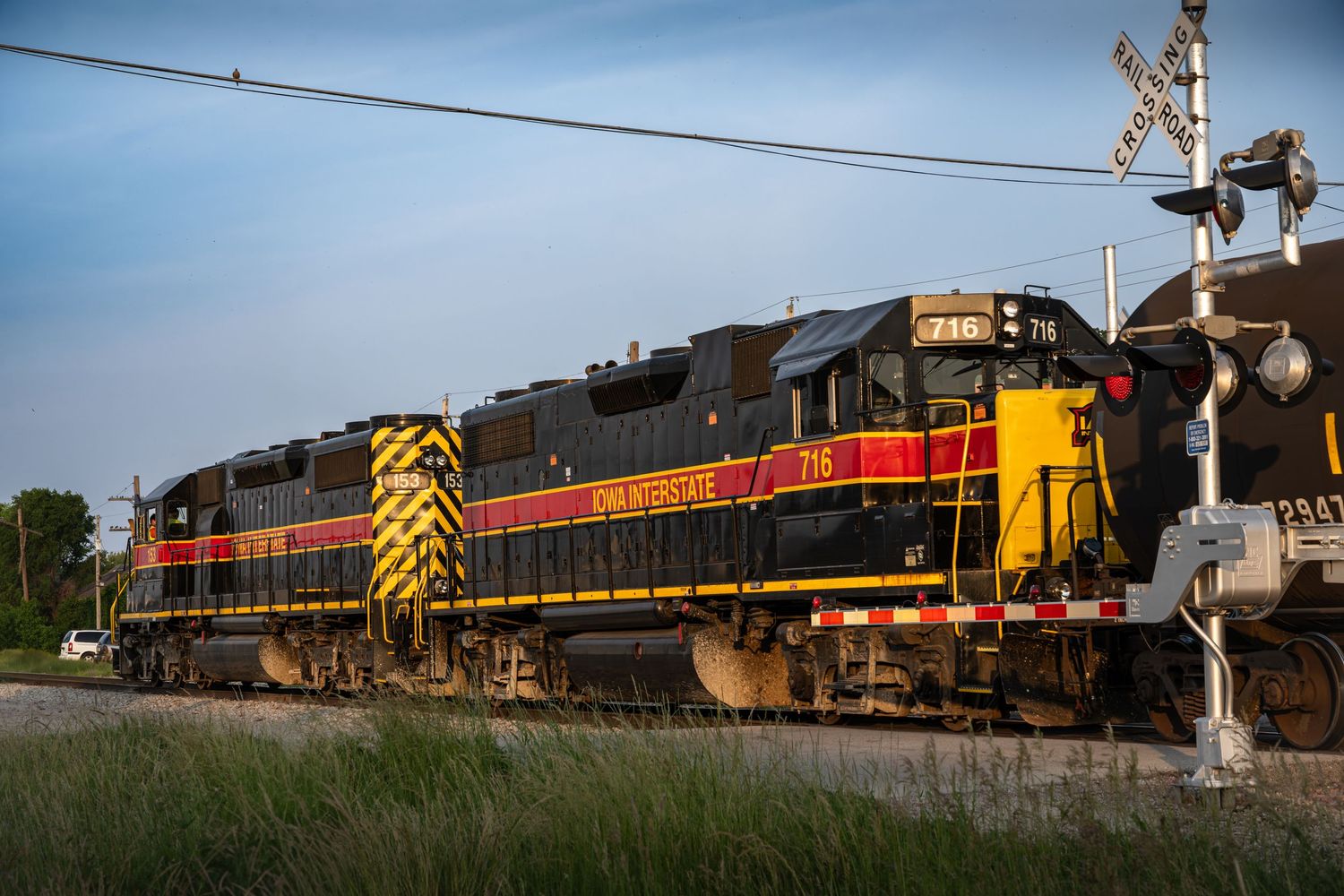 Freight train with mixed locomotives moves along rural tracks at dusk. Iowa Interstate Moline Illinois.