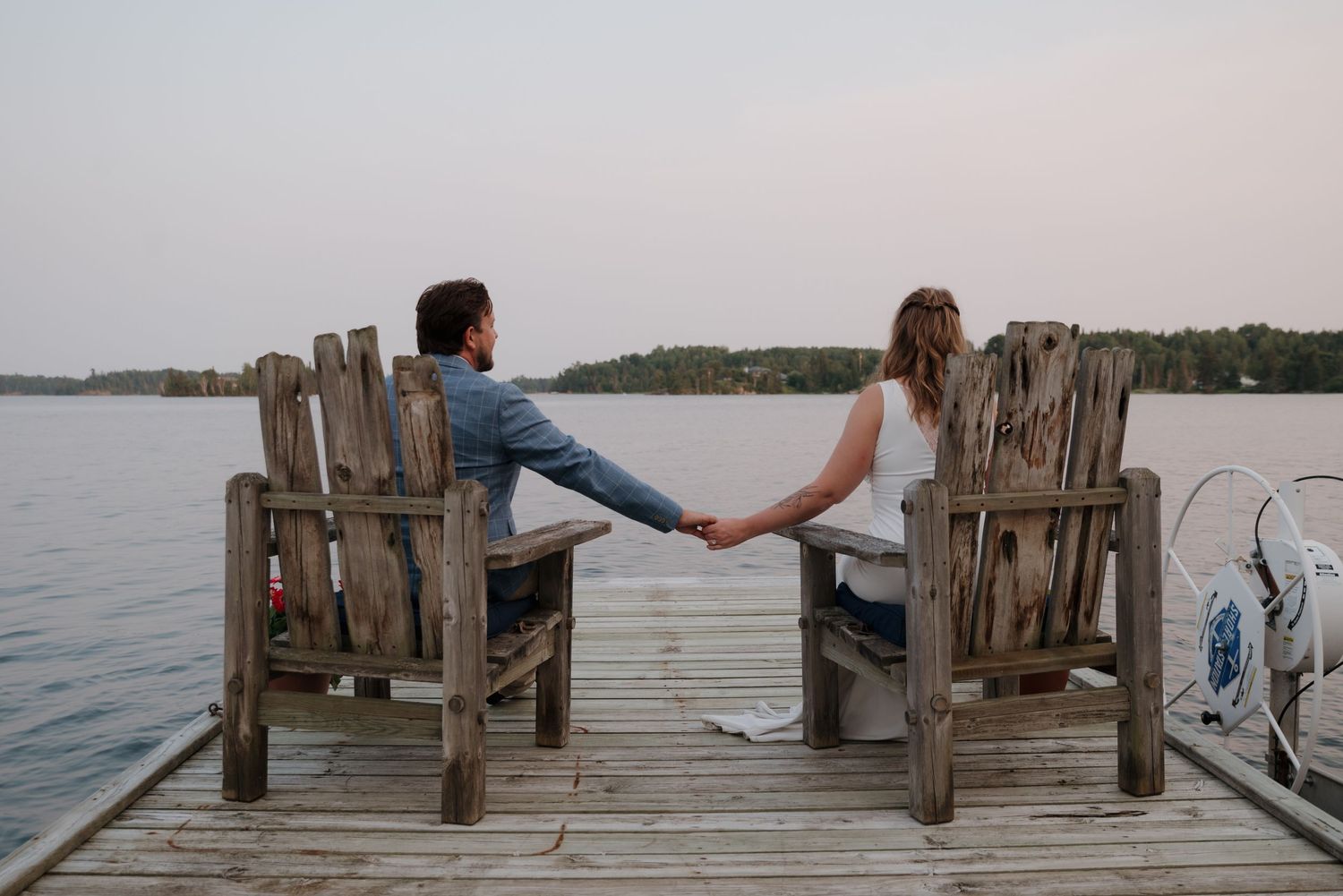 A wooden dock extends into a calm lake during sunset.