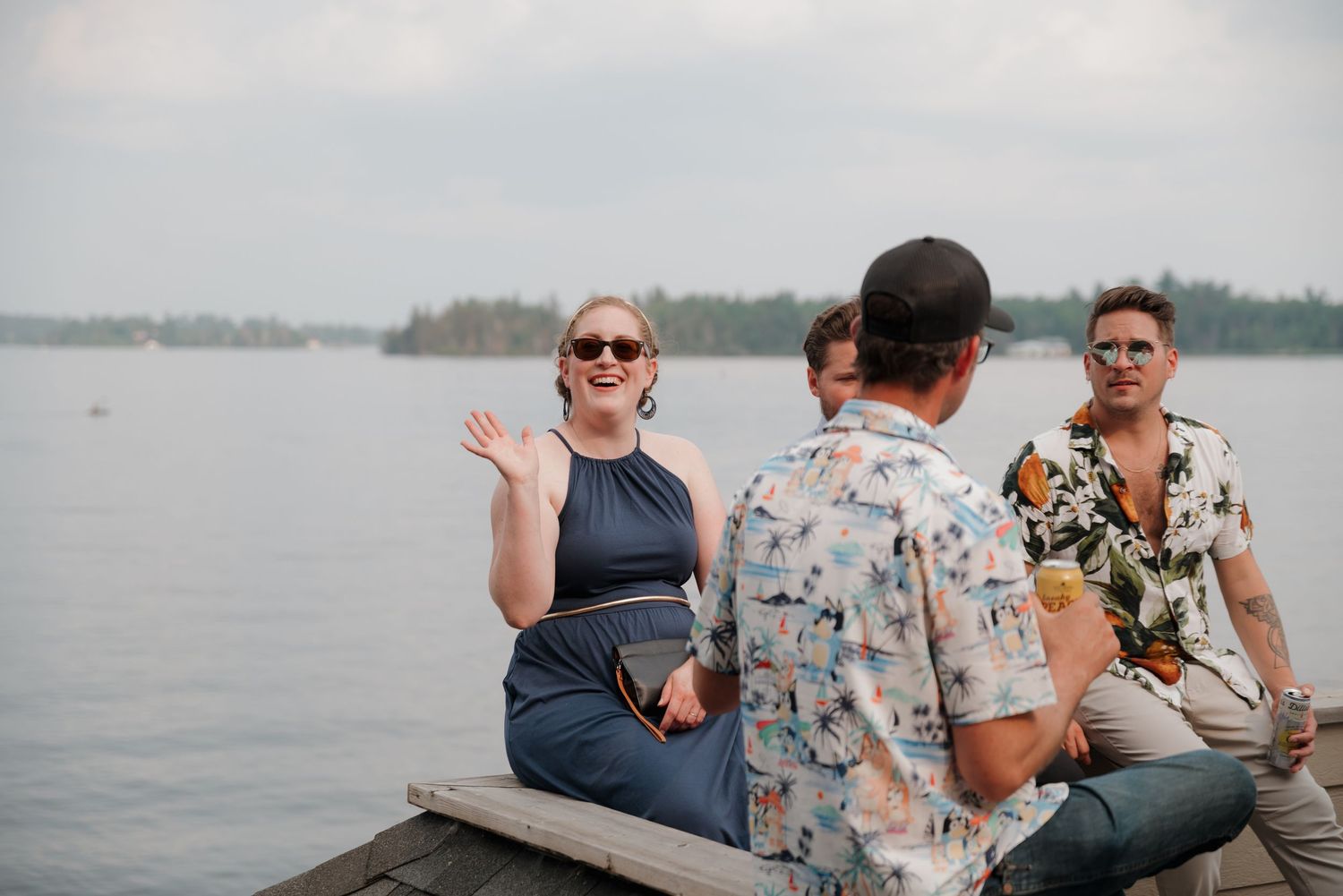 People enjoying a casual gathering and conversation while sitting on a dock by a serene lake.