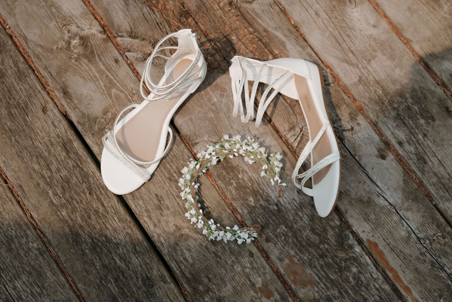Wedding accessories including white shoes and baby's breath flowers arranged on weathered wooden planks.
