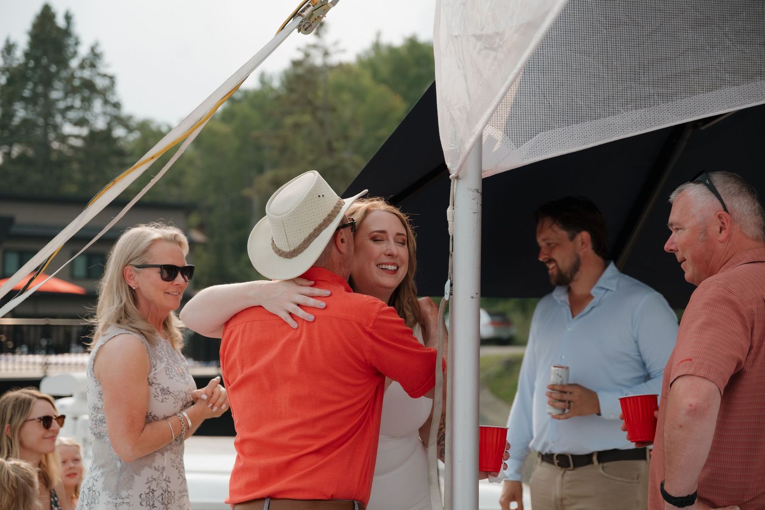People gather and socialize at an outdoor event under a white tent.