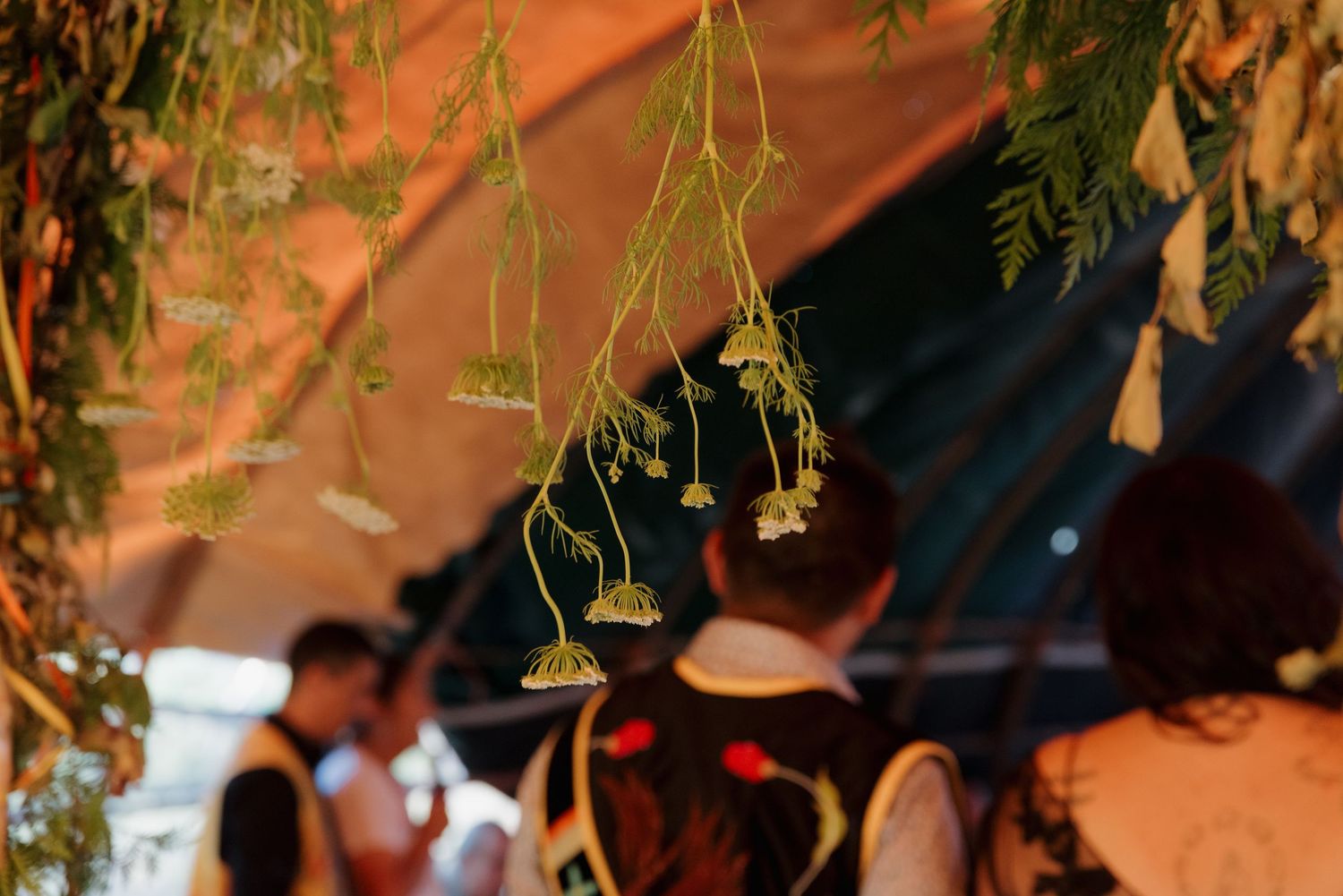 Decorative hanging plants and flowers suspended from a canopy at an outdoor cultural event.