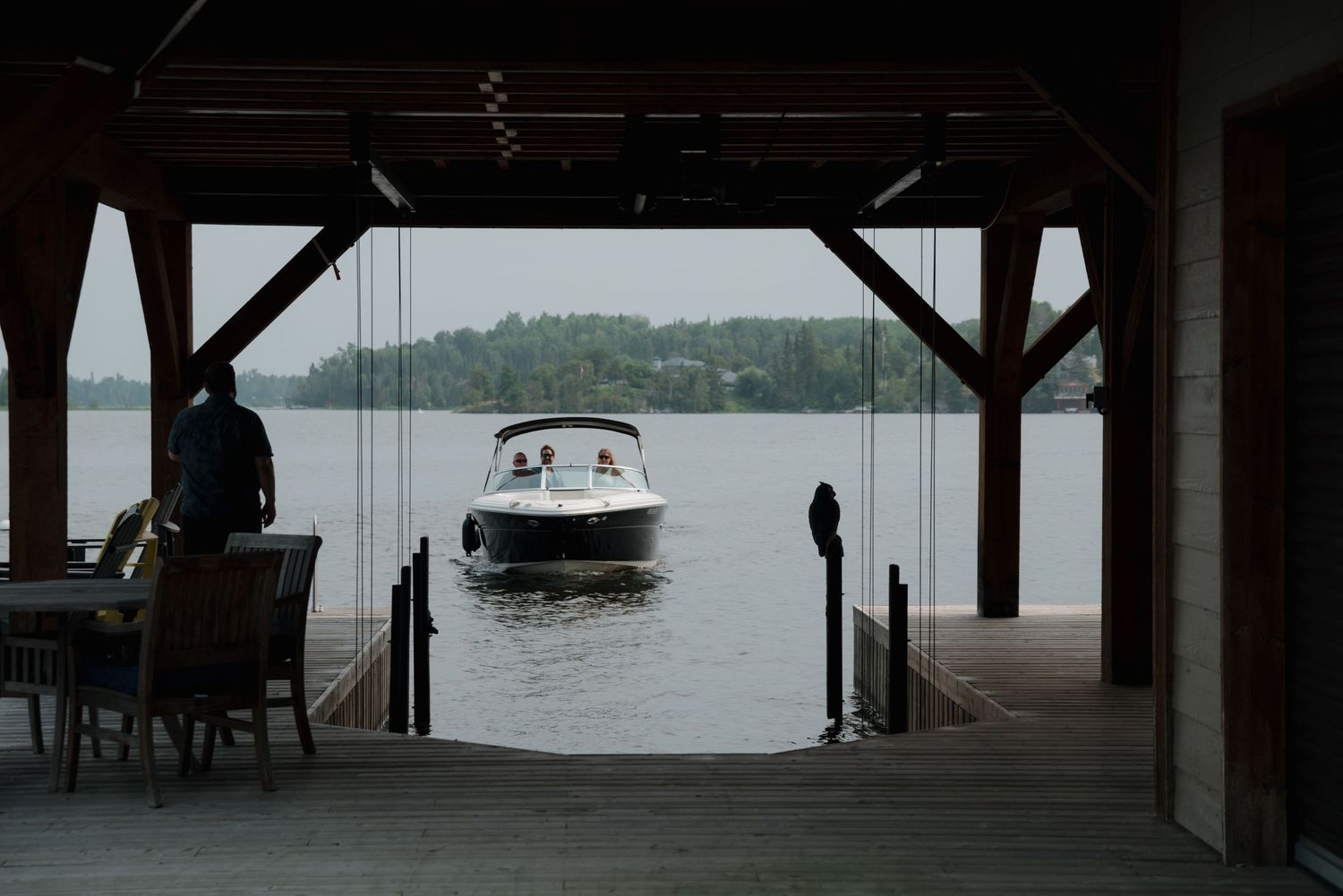 Covered dock on a lake with boats visible in the distance through the wooden structure.