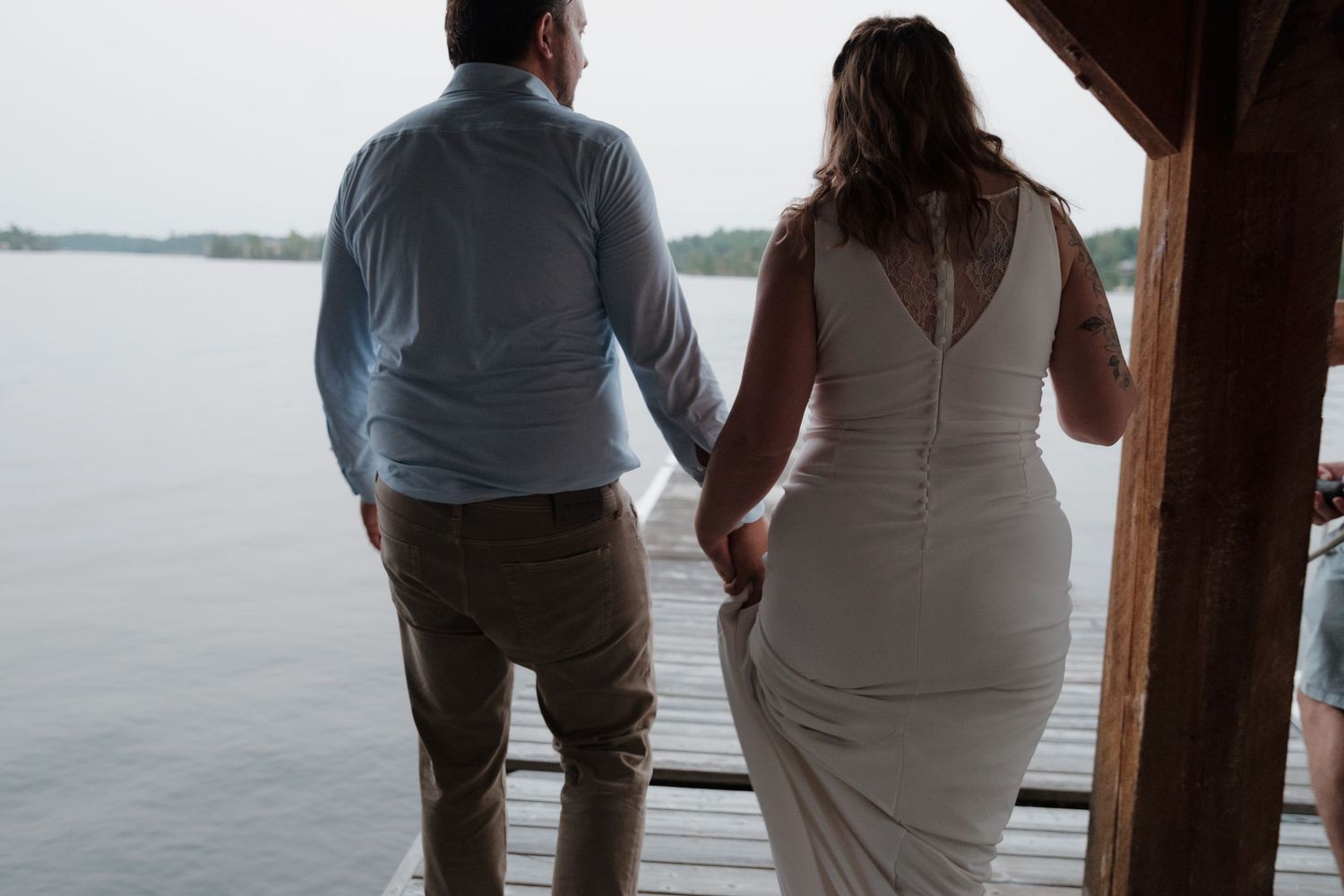 Silhouetted couple standing in a covered porch overlooking a lake view.