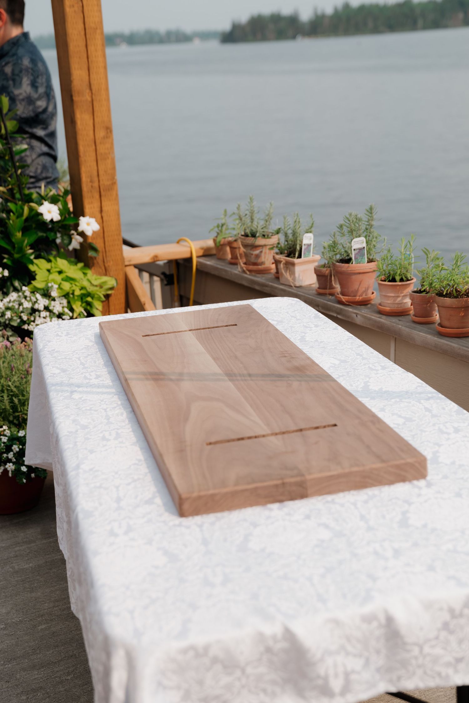 A guest book table setup with a white tablecloth and wooden box overlooking a lake.