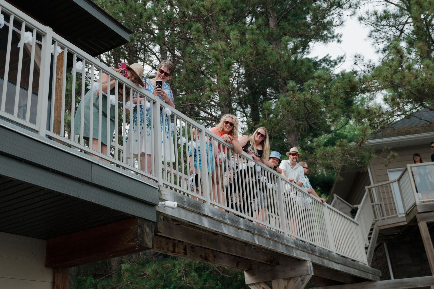 Wedding guests gathered on balcony overlooking lake during celebration.