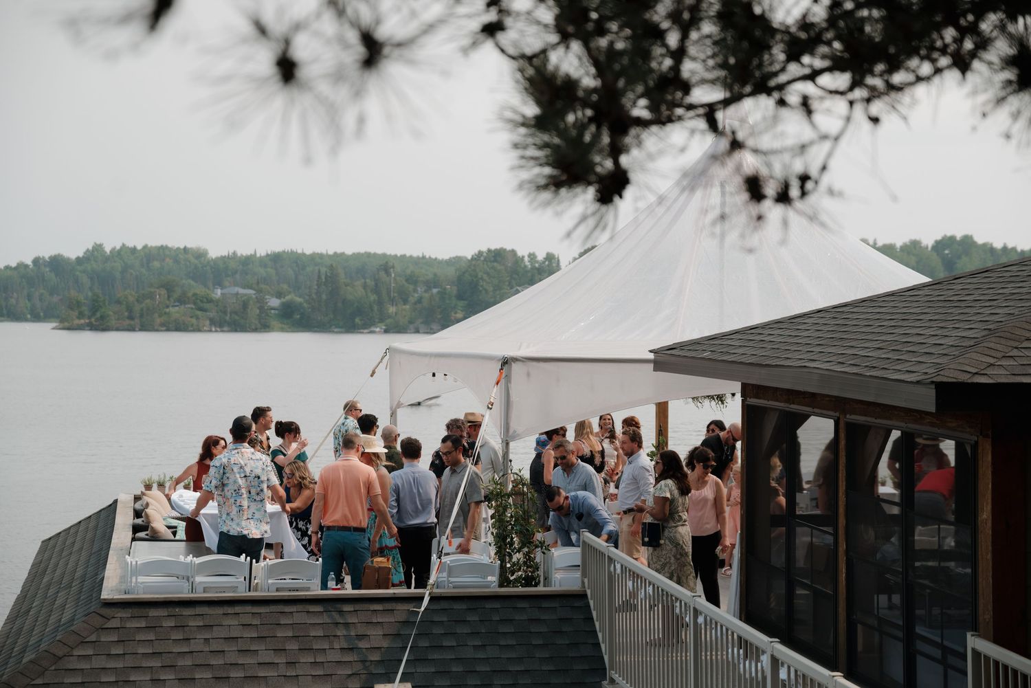 Wedding guests mingle and socialize on a covered outdoor patio during a reception celebration.