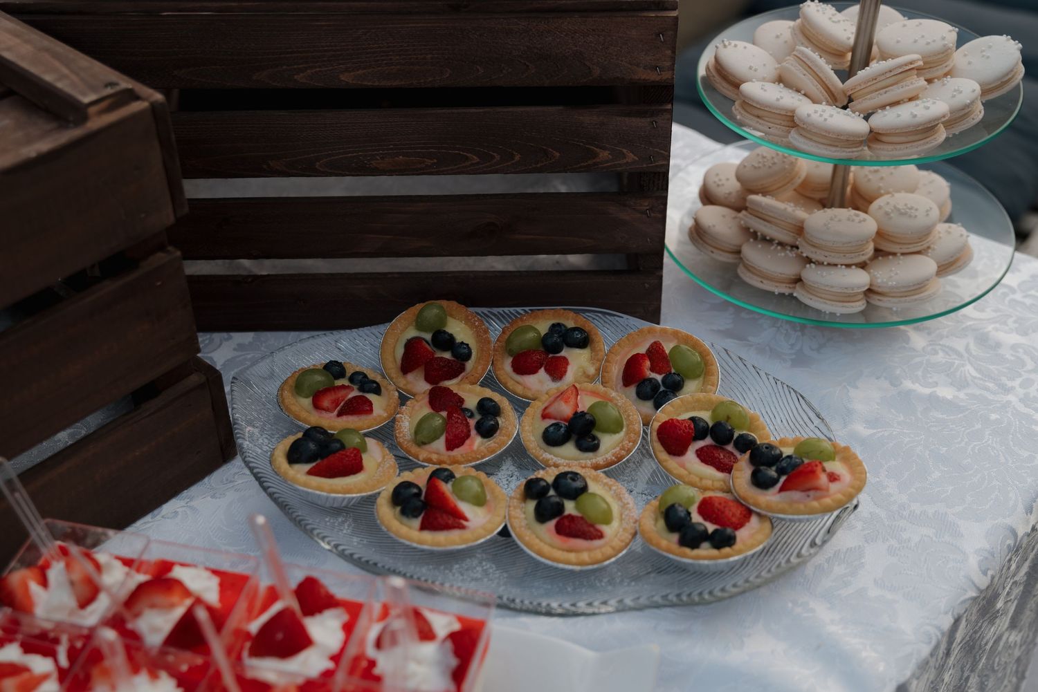Assorted desserts and pastries displayed on white serving platters at an event.