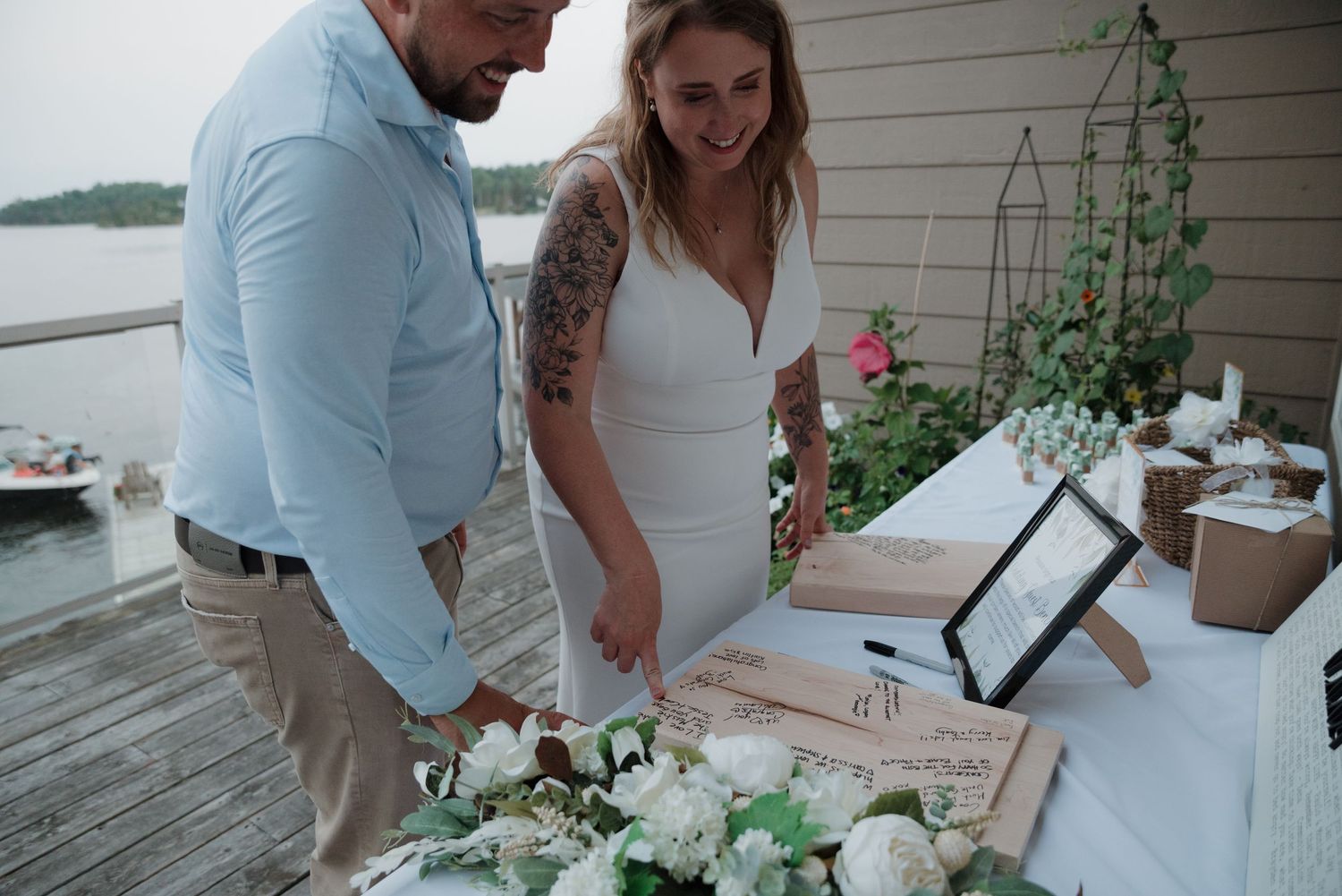 Couple signs marriage documents at an outdoor waterfront ceremony.