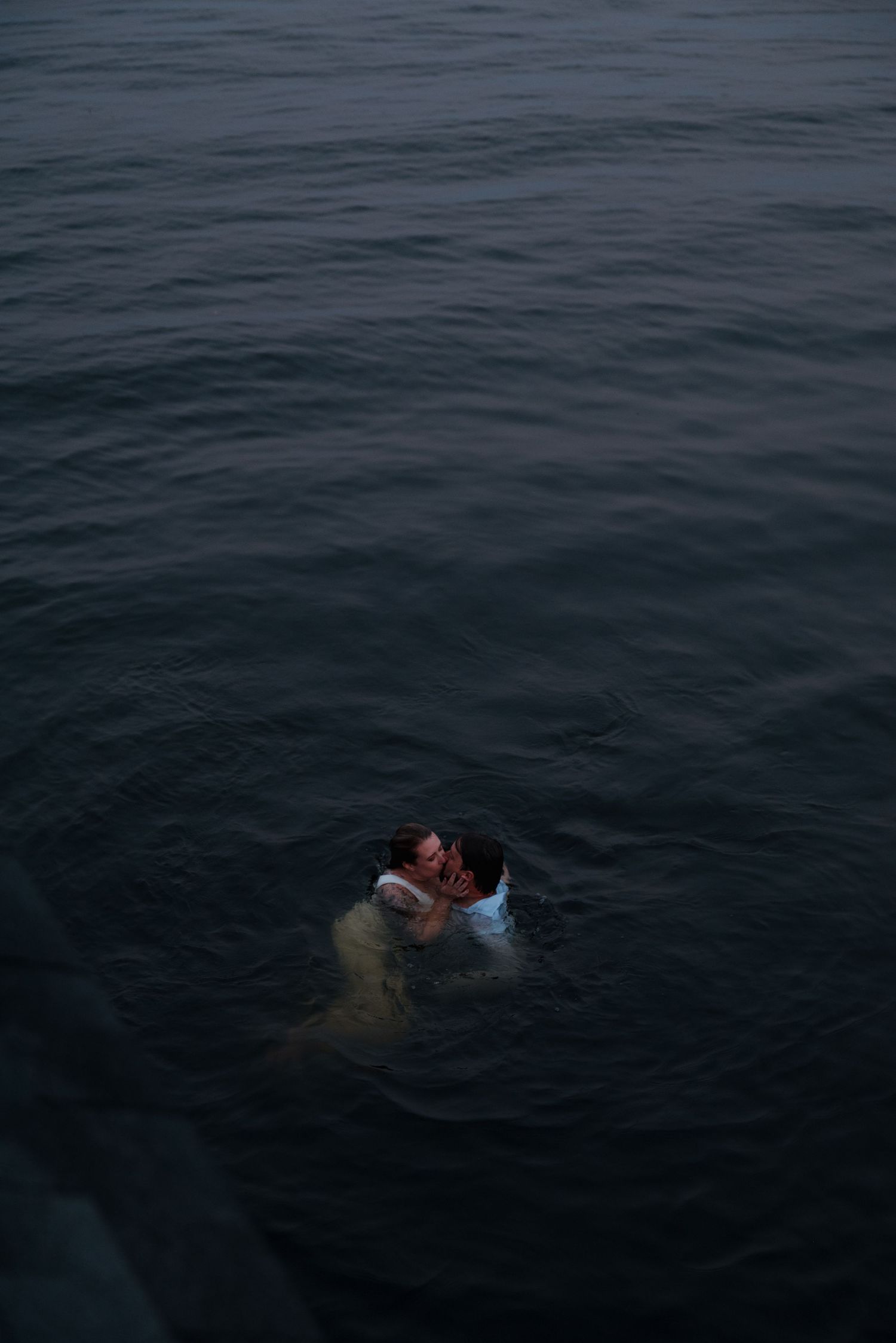People swimming in dark blue waters during an evening lake activity.