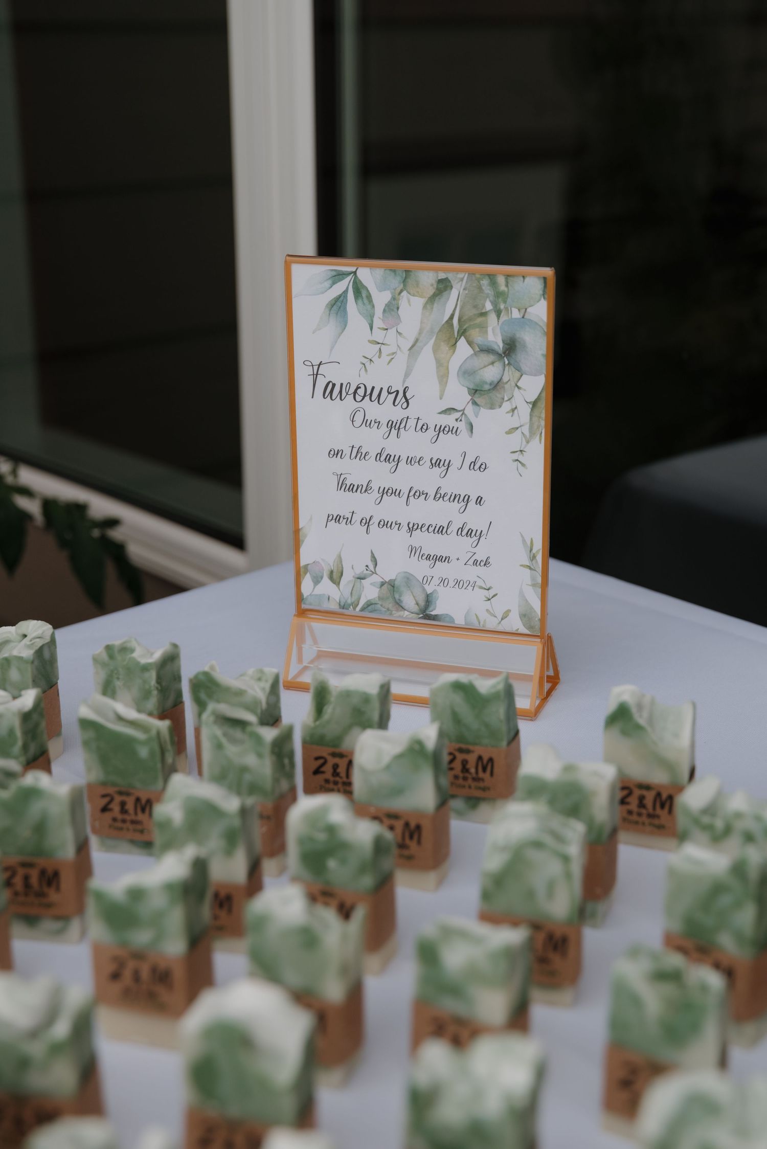 Wedding favor place cards with greenery design displayed in neat rows on a white table.