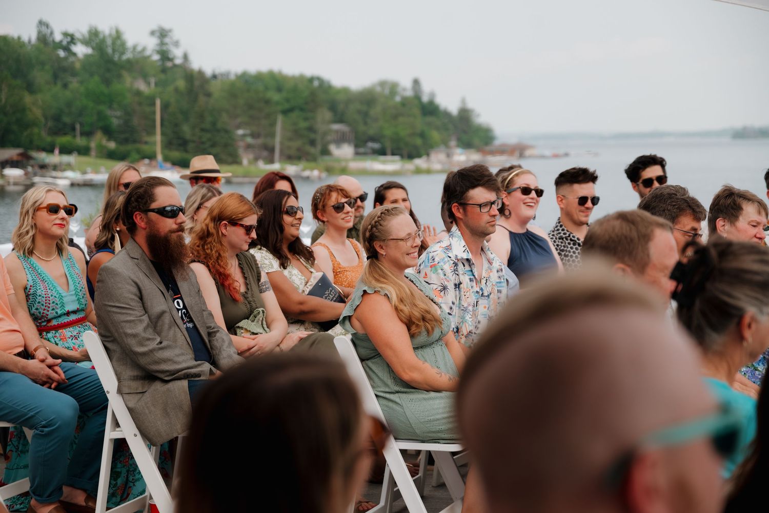 Crowd of wedding guests watching a celebration at an outdoor waterfront venue.