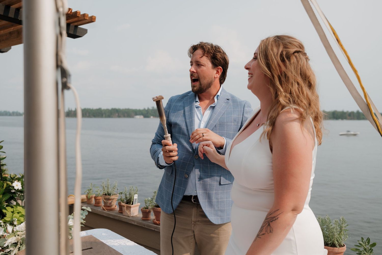 Wedding ceremony taking place on a waterfront deck with lake views in the background.