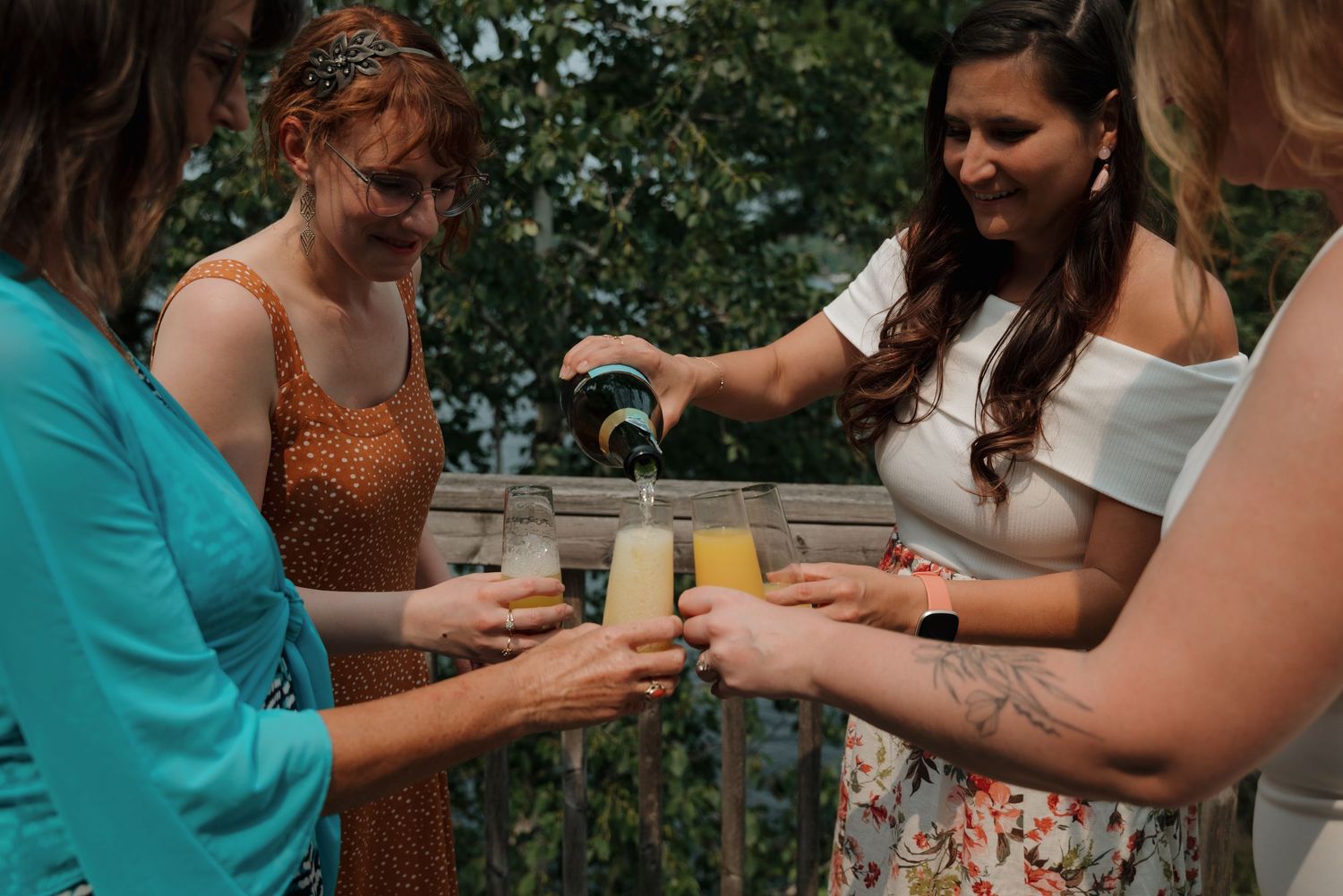 Wedding guests raise their glasses in a celebratory toast during an outdoor reception.