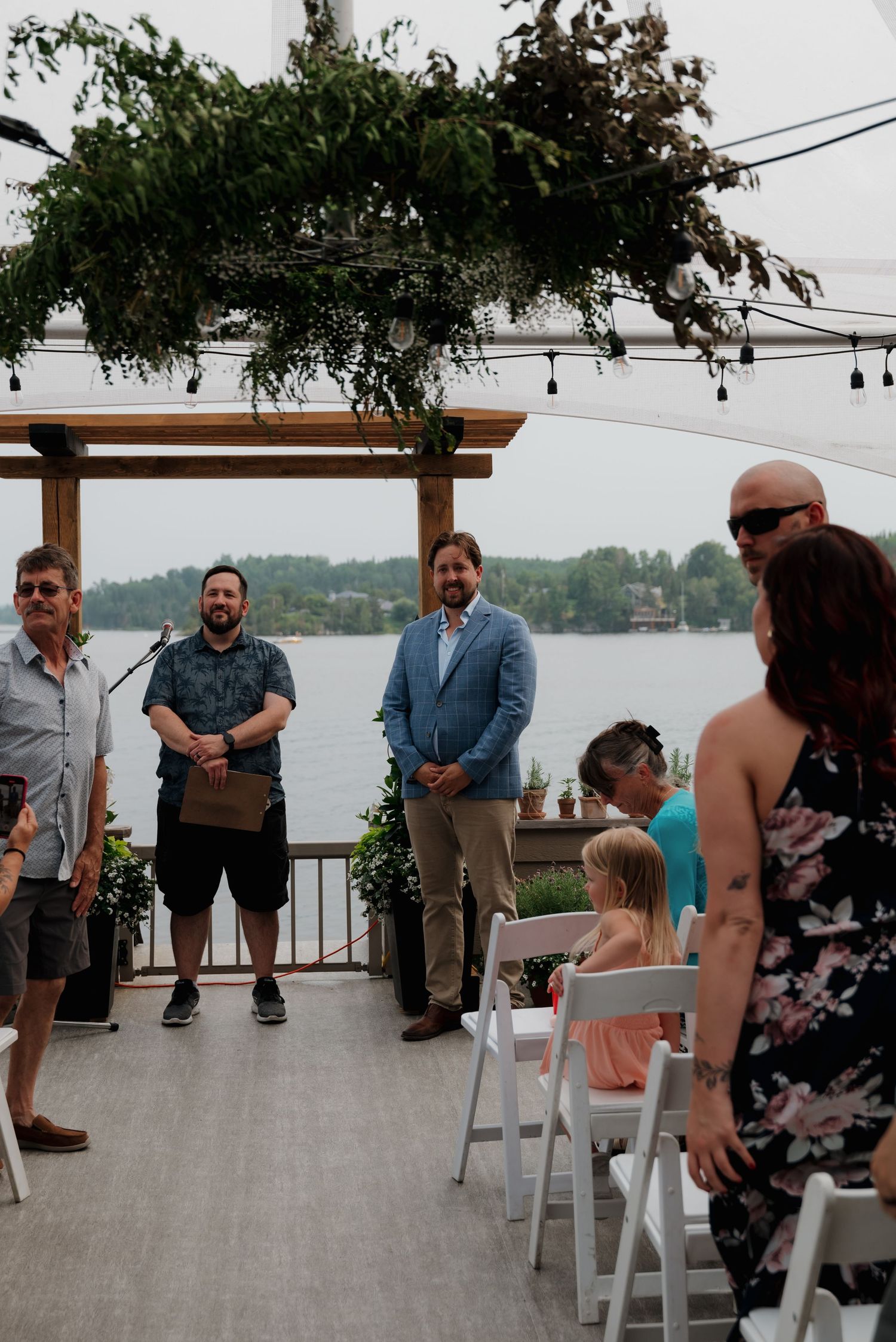 Wedding ceremony setup with white chairs and floral decorations overlooking a scenic waterfront.