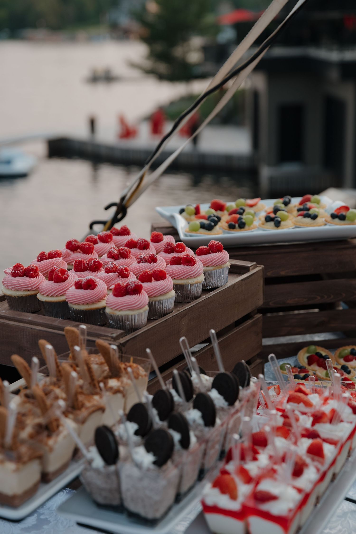 Colorful desserts and cupcakes displayed on wooden serving trays at a catering event.