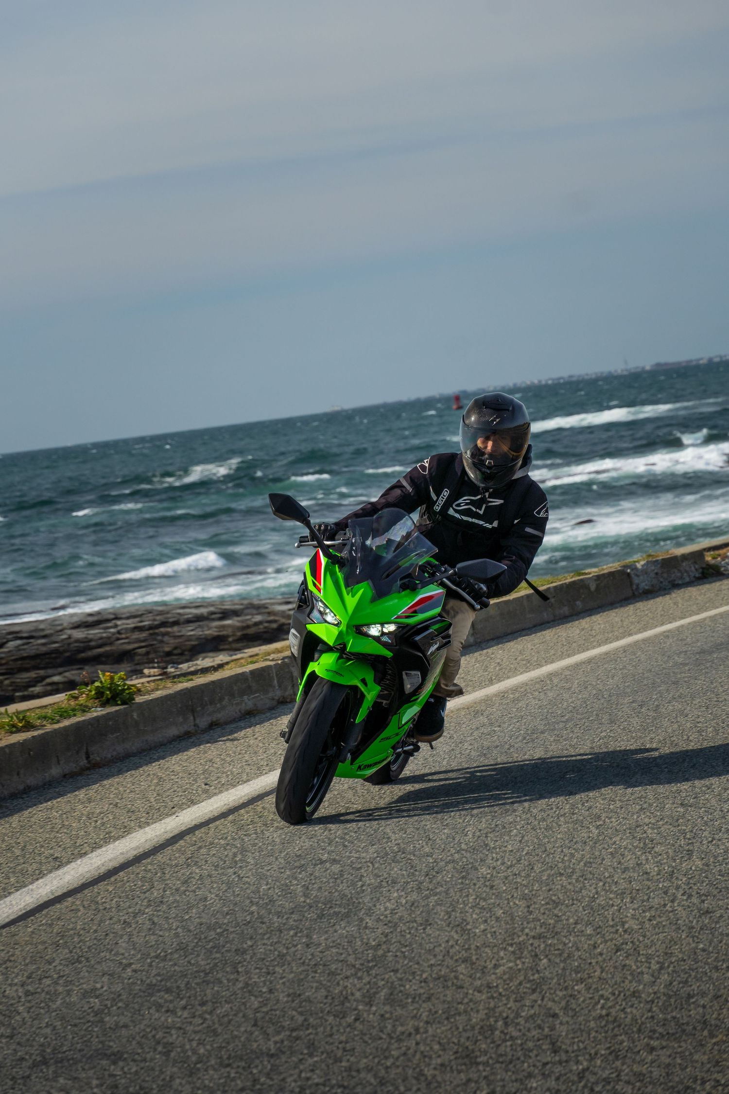 Green Kawasaki Ninja 500 cruising with the beautiful ocean in the background