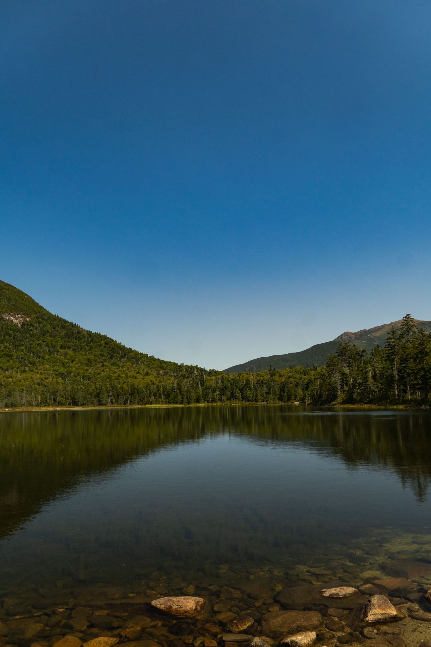 Moutains reflecting on pond not a single cloud in the sky