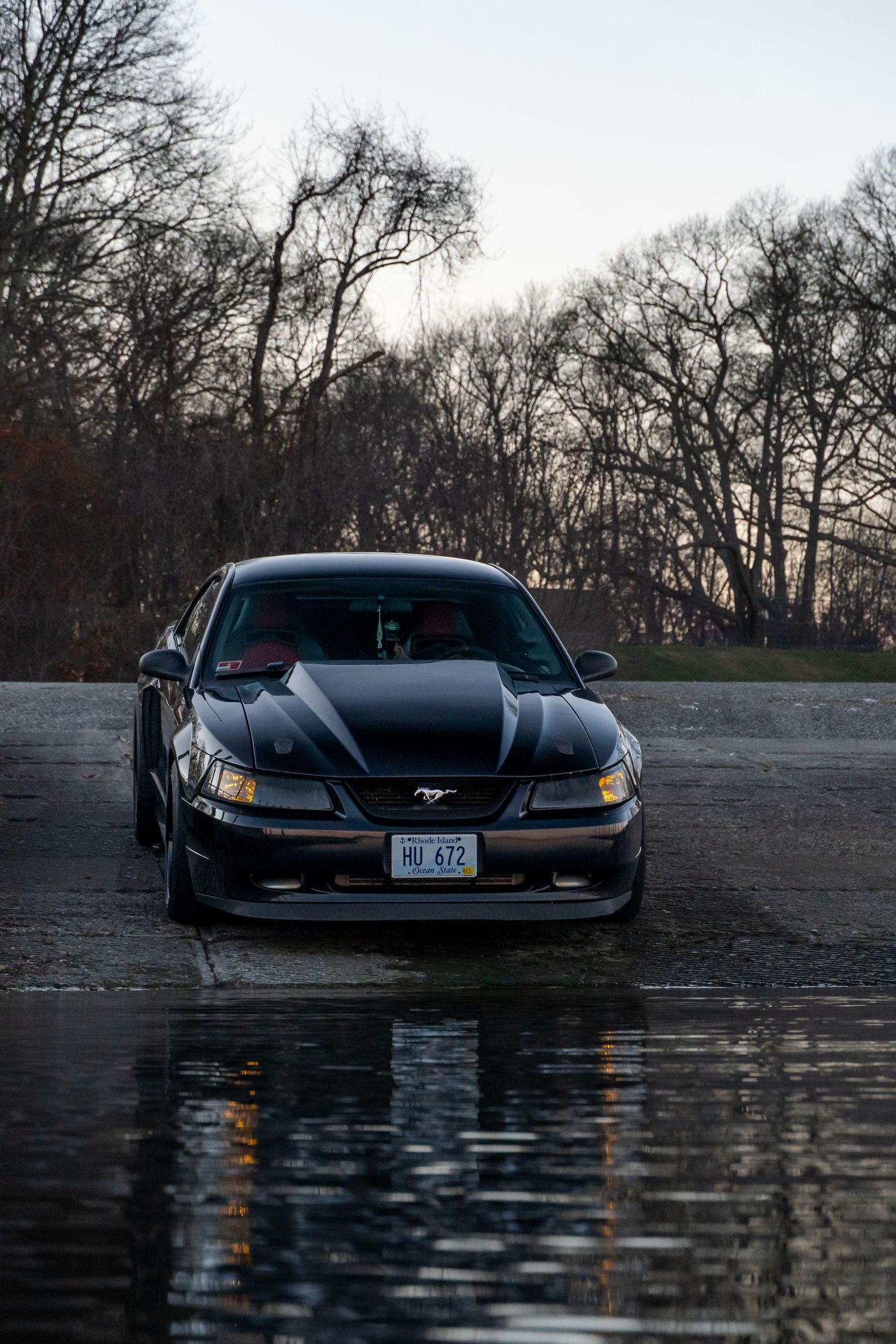 2002 Mustang GT parked at the end of a boat dock with a beautiful reflection