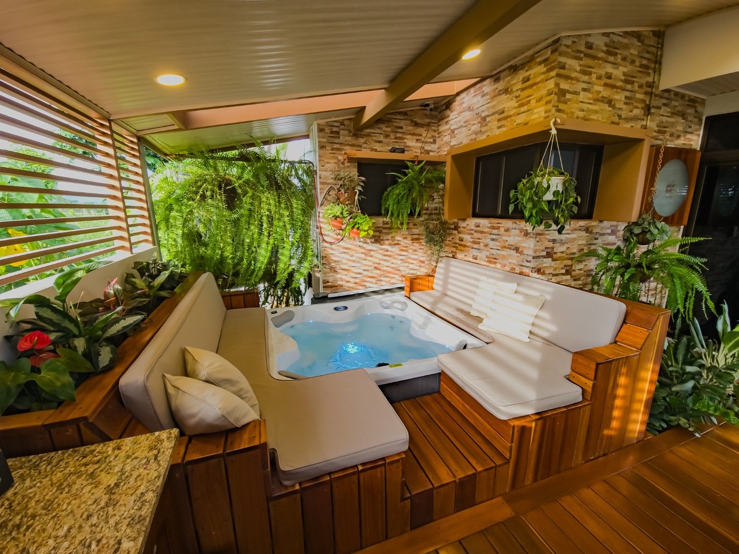 Indoor spa area with wooden deck, stone walls, and hanging plants creating a natural ambiance.