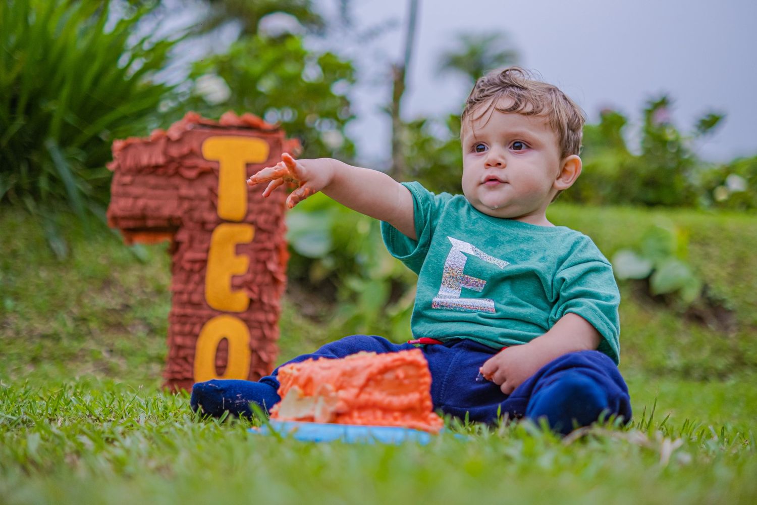 Toddler in green shirt playing with colorful toy blocks on grass.