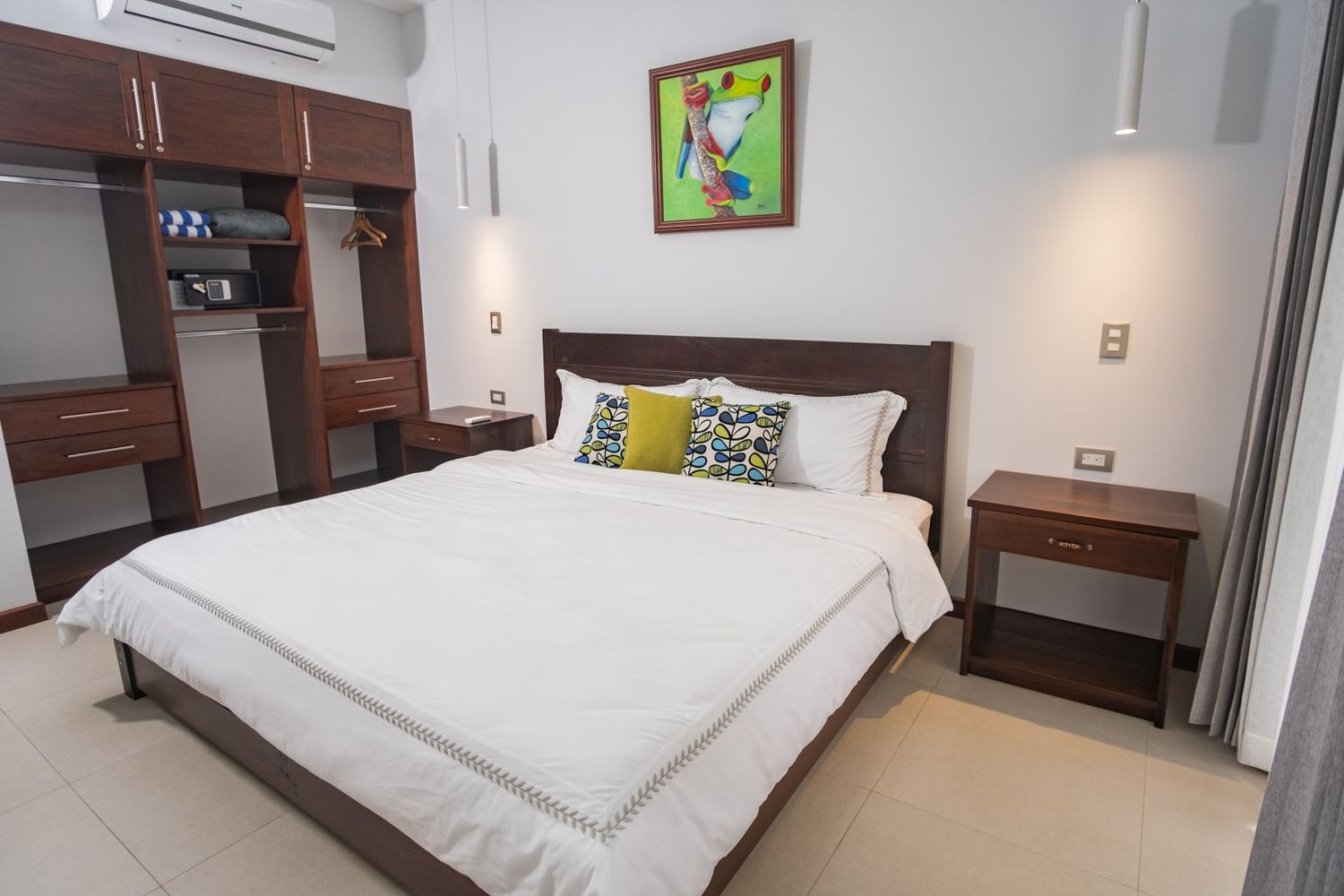 Contemporary bedroom with white bedding, wooden headboard, and minimalist decor.