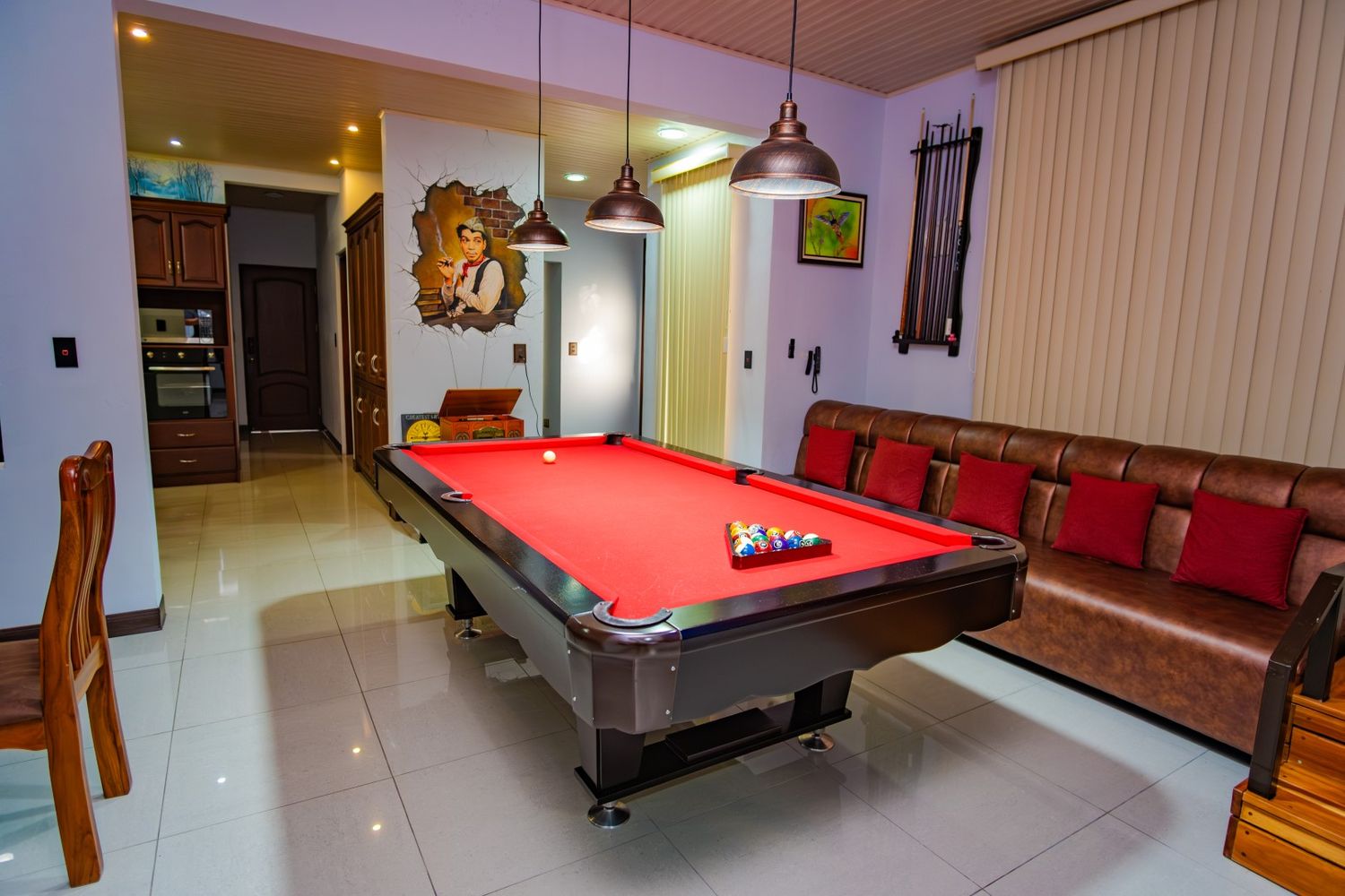 Game room with red pool table, pendant lighting, and wooden furniture.