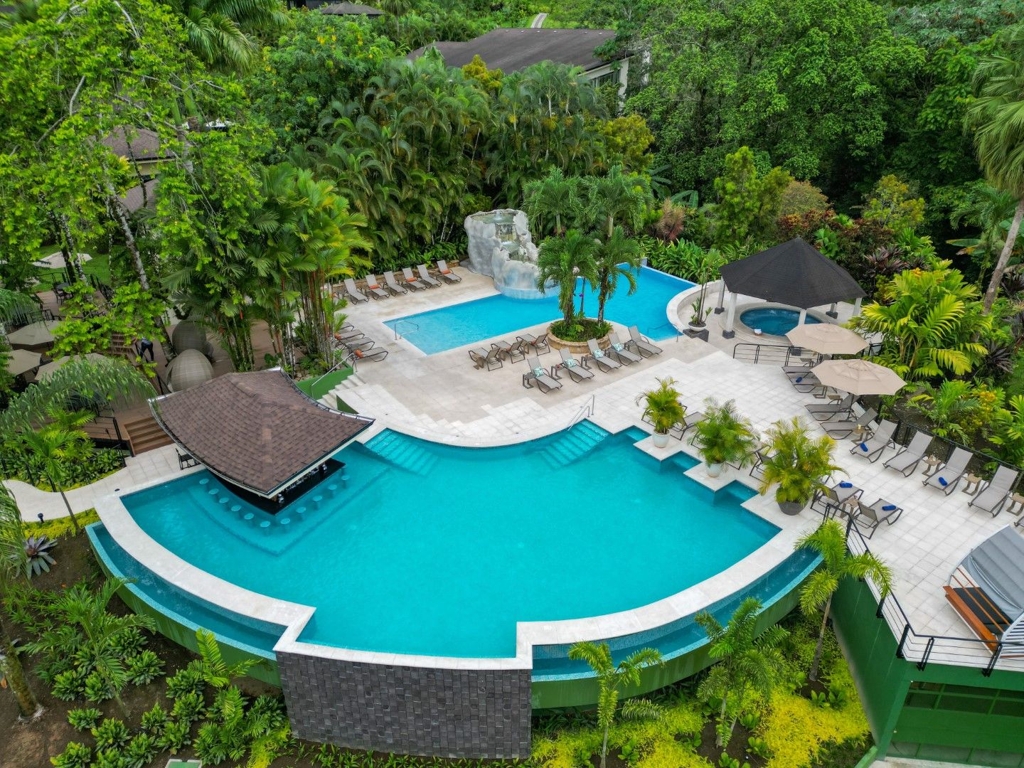 Aerial view of a resort featuring multiple turquoise swimming pools surrounded by tropical landscaping.