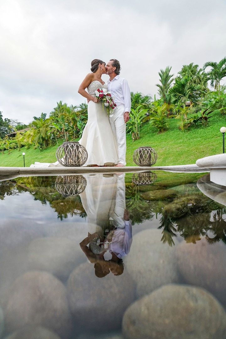 Wedding couple sharing an intimate moment by a reflective pool with tropical landscaping in the background.