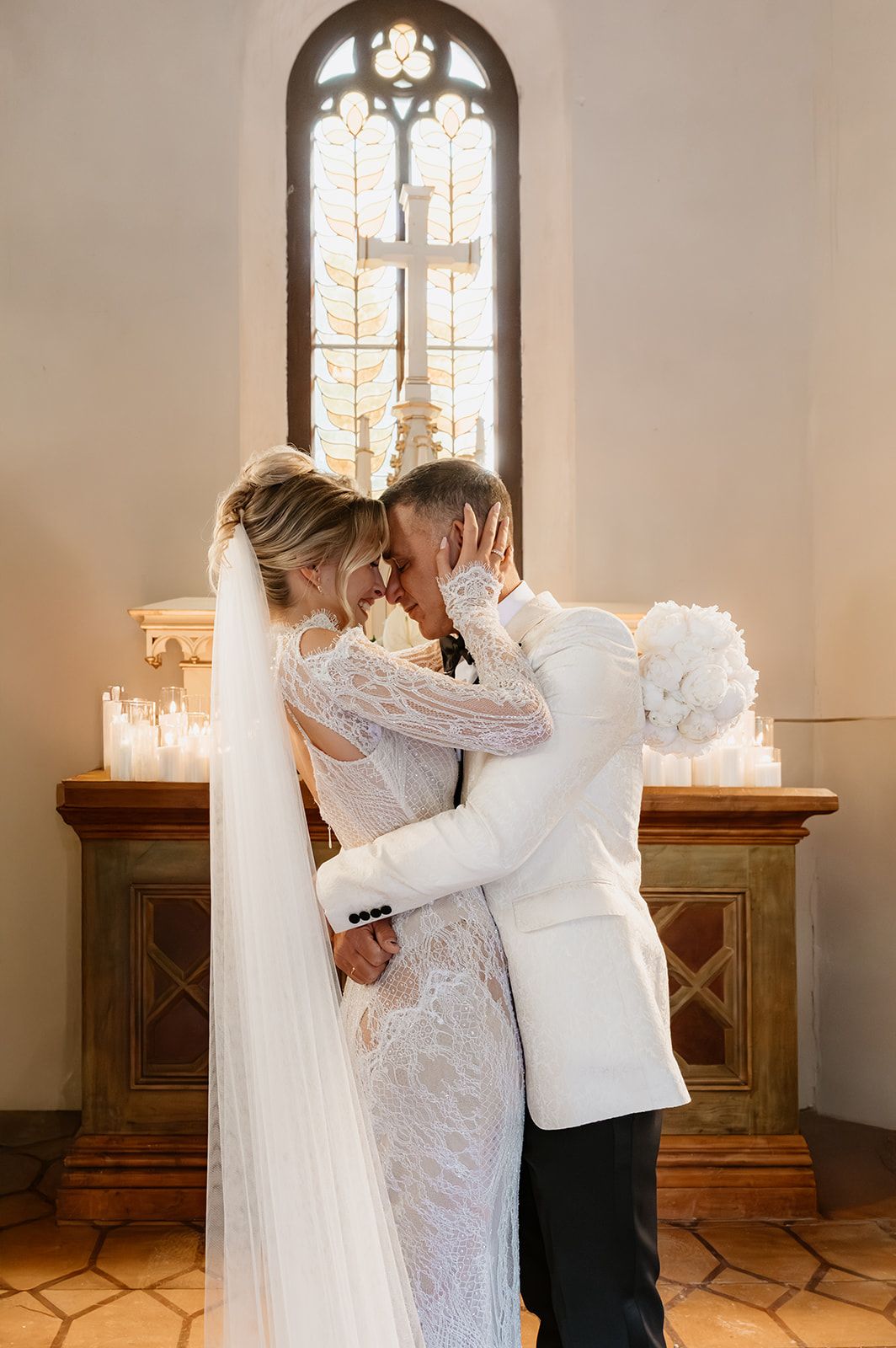 Romantic wedding moment captured in a church with arched windows and wooden details.