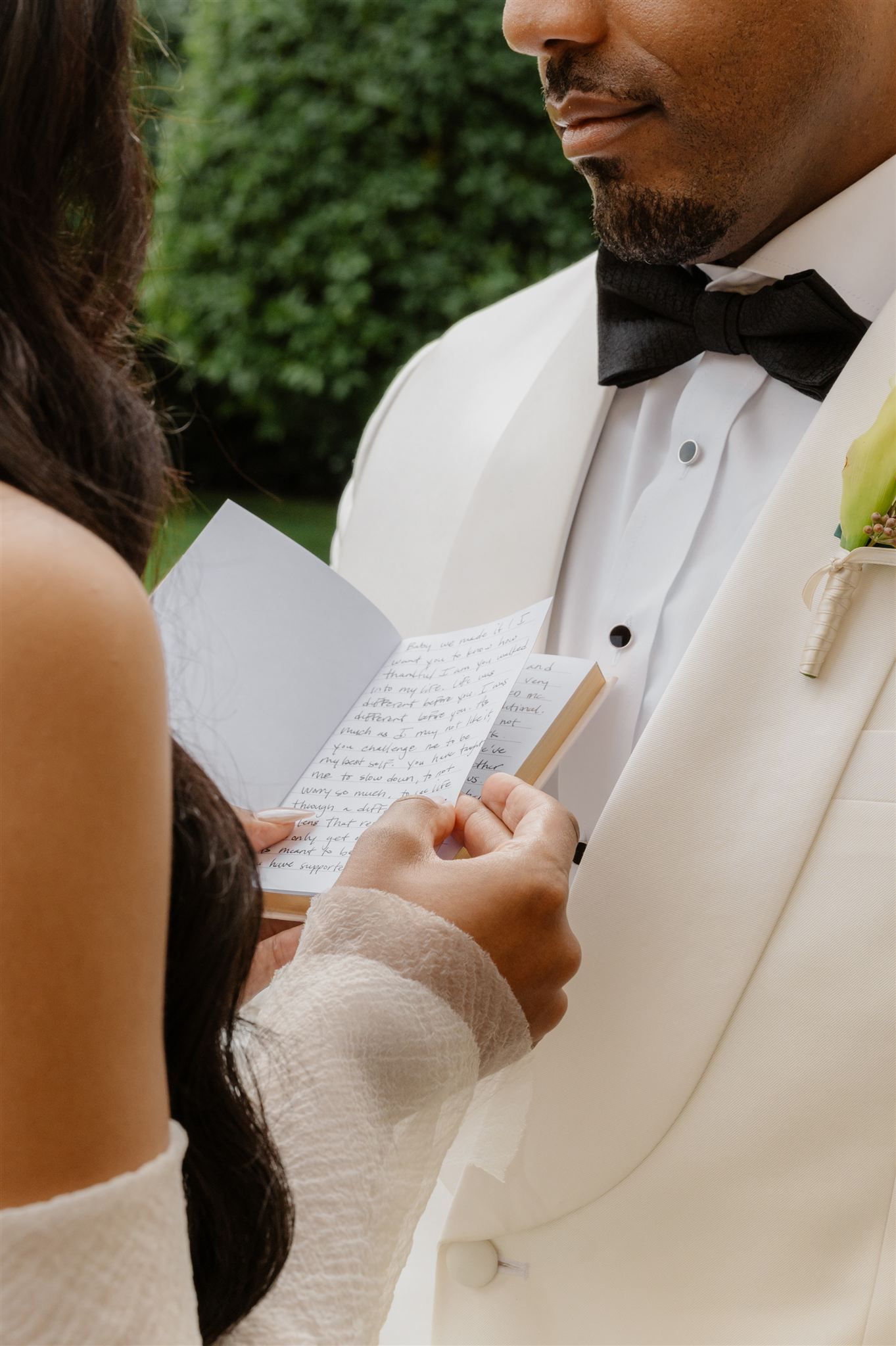 Close-up shot of wedding vows being read from handwritten cards during an outdoor ceremony.