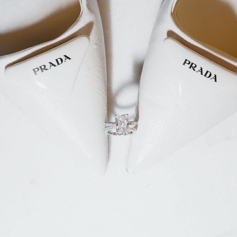 White Prada bridal shoes with sparkling diamond engagement ring displayed.