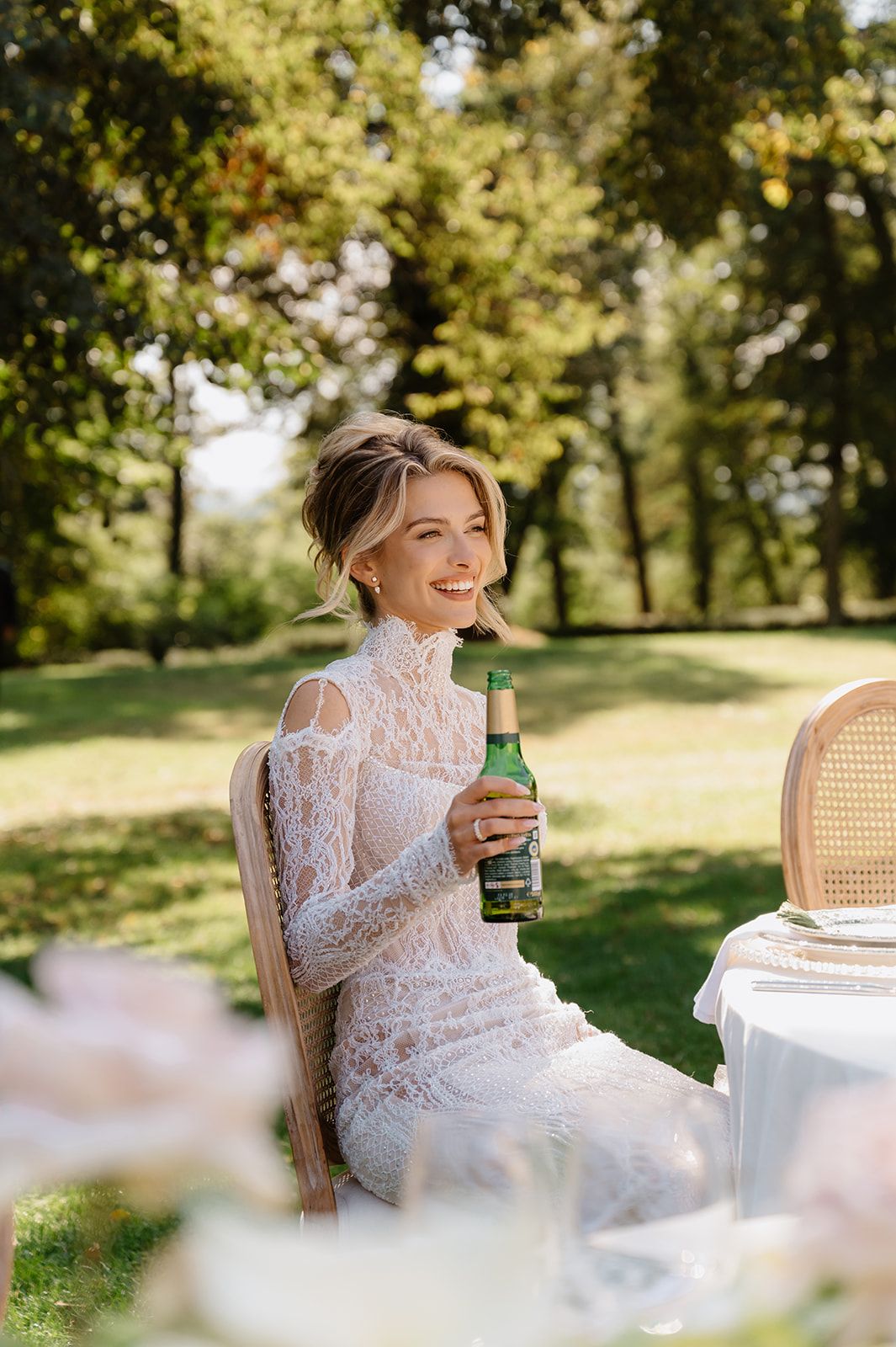 Elegant outdoor wedding reception with white parasols and table settings in natural sunlight.