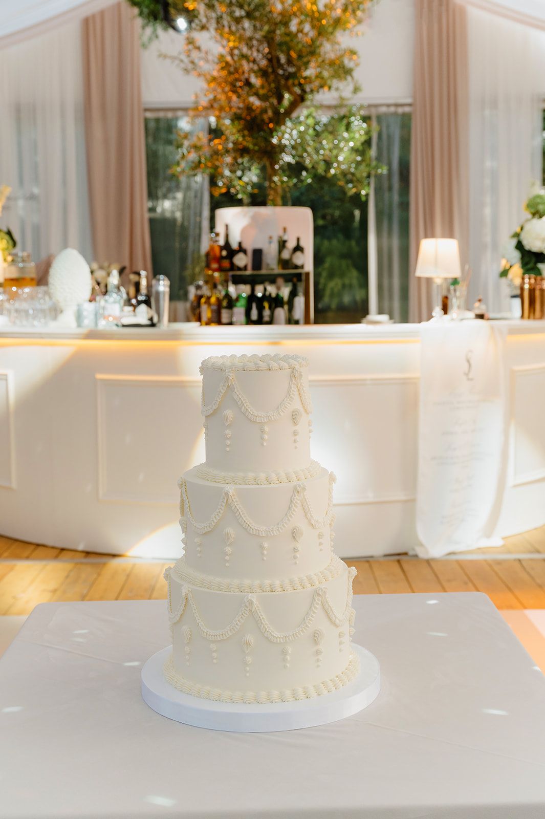 Classic white tiered wedding cake displayed at elegant reception venue.
