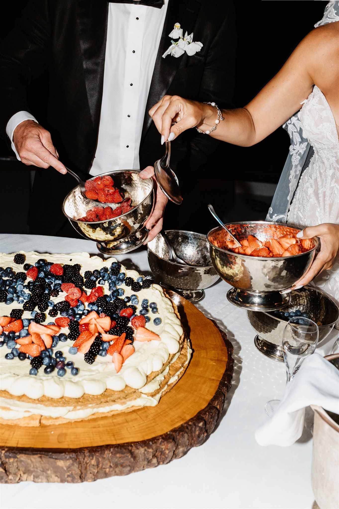 Fresh berries and cream being arranged on a rustic wooden serving platter.